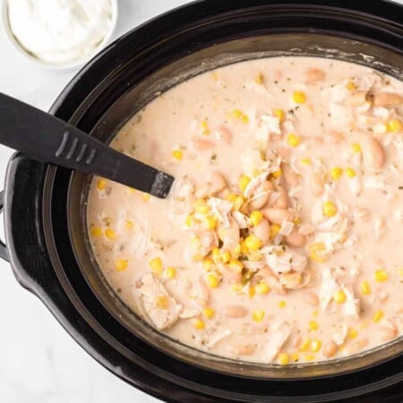 Creamy chicken tortilla soup in a slow cooker from above on a counter with a ladle up close.