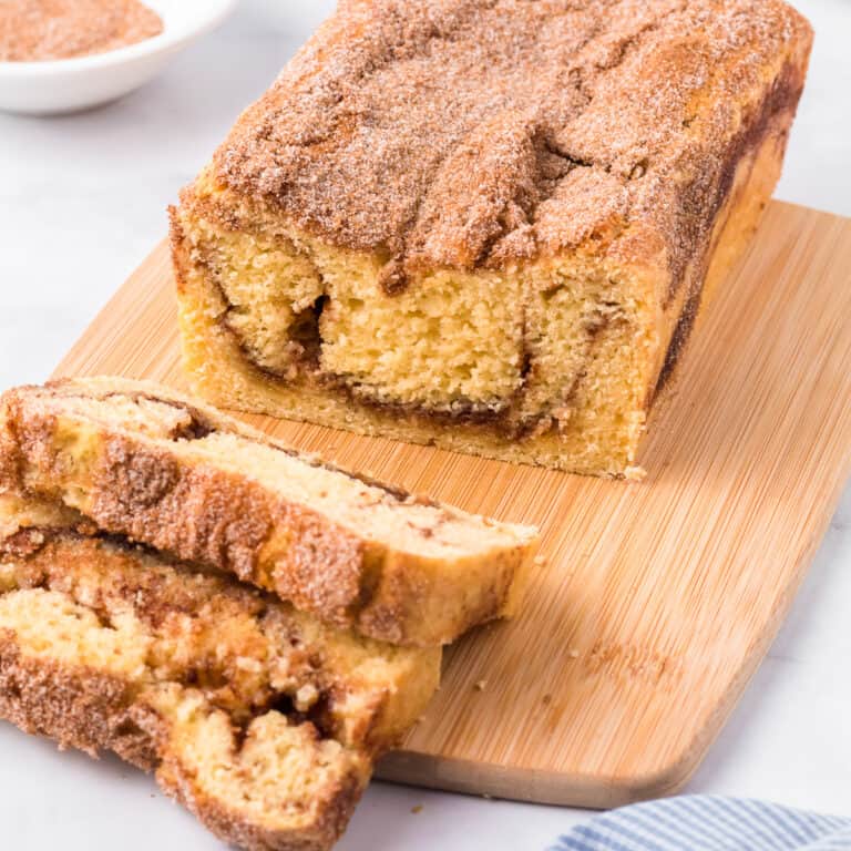 Close up angle of Snickerdoodle bread with several sliced cut from the loaf on a cutting board.