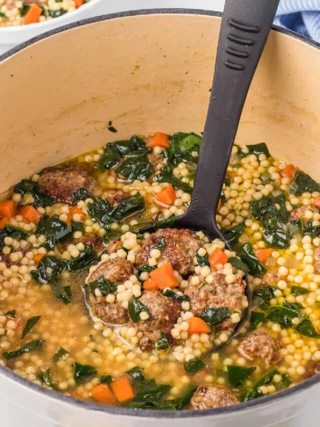 A pot of soup with meatballs and spinach.