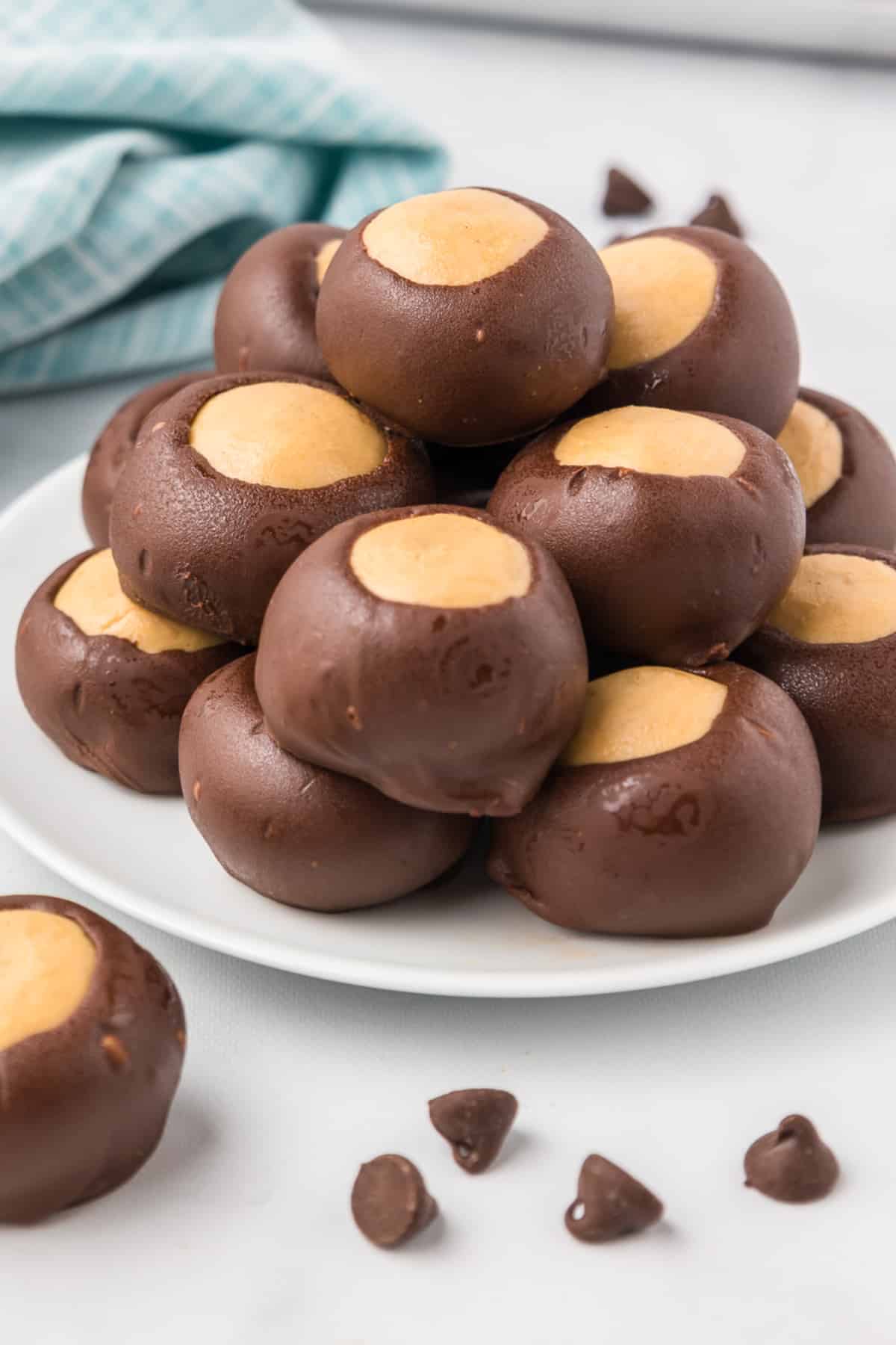 Buckeyes stacked high on a plate from the side on a kitchen counter.