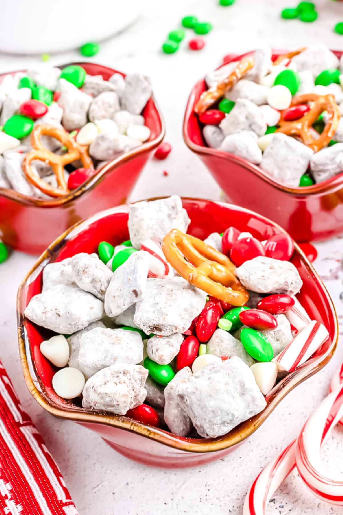 Reindeer Chow Chex Mix in three red individually sized bowls from the side.