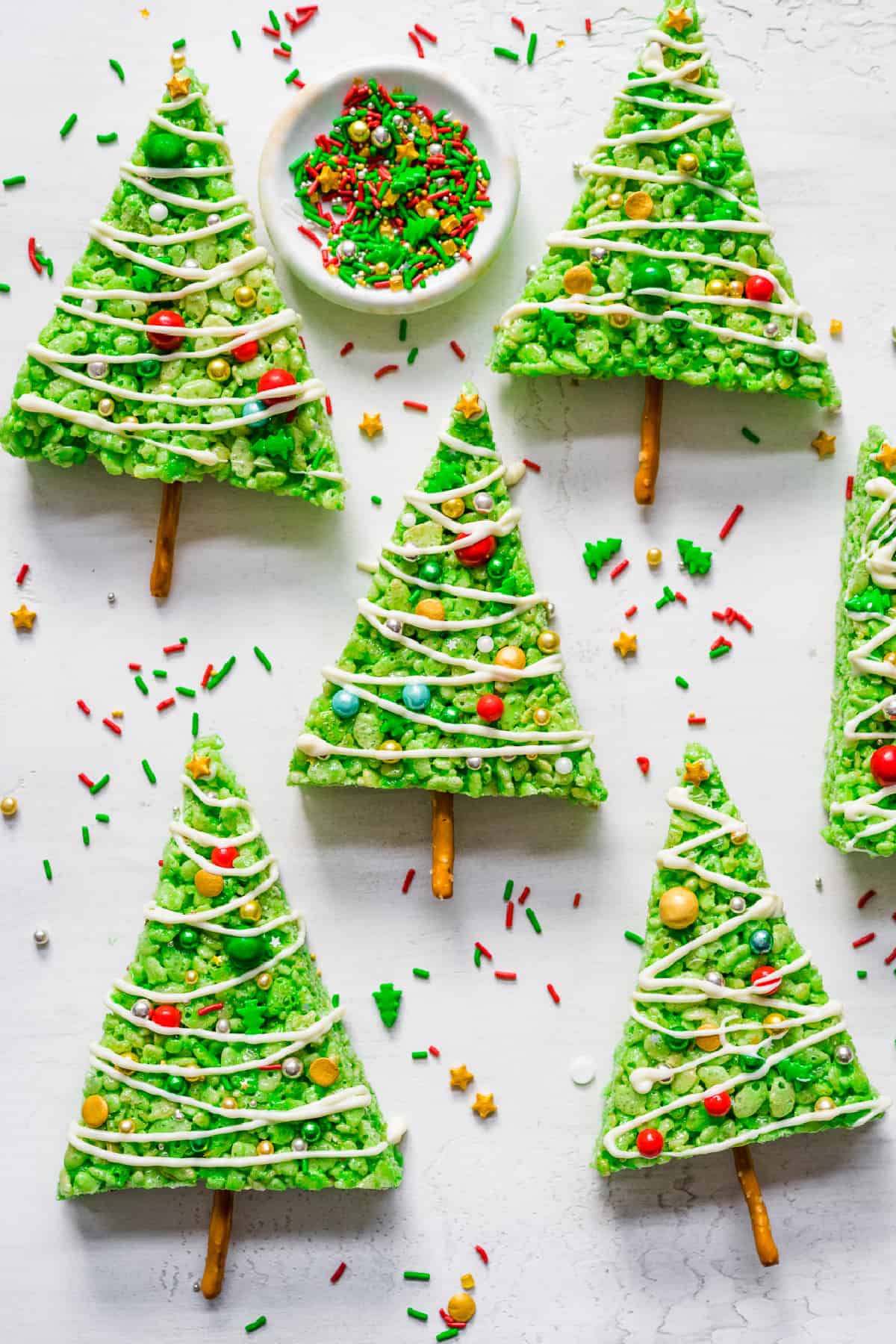 Green rice krispie treats shaped land decorated like Christmas trees with sprinkles on a counter from overhead.