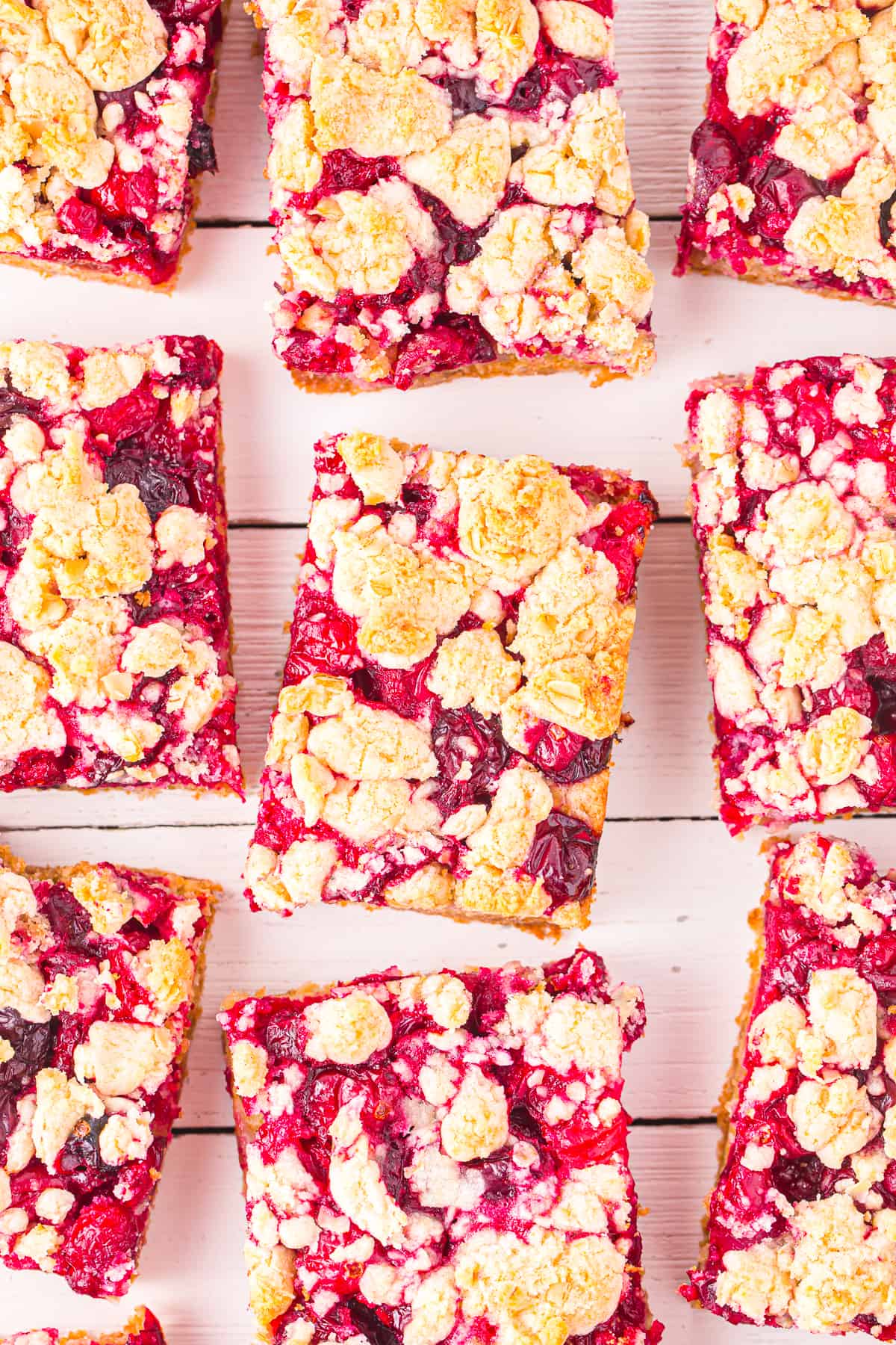 Nine cranberry crumble bars sliced and spaced apart on a counter from overhead.
