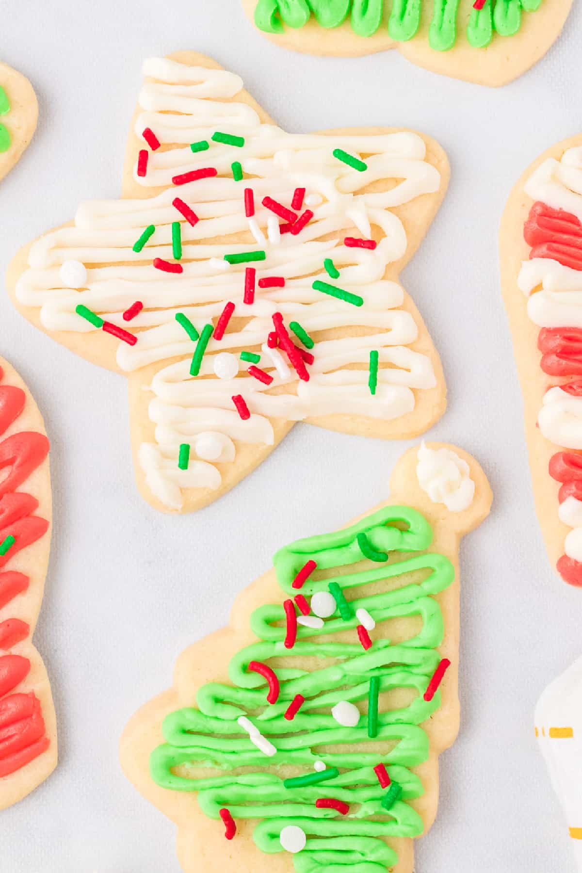 Frosted cutout cookies shaped like a star and a tree frosted with Christmas colored sprinkles.