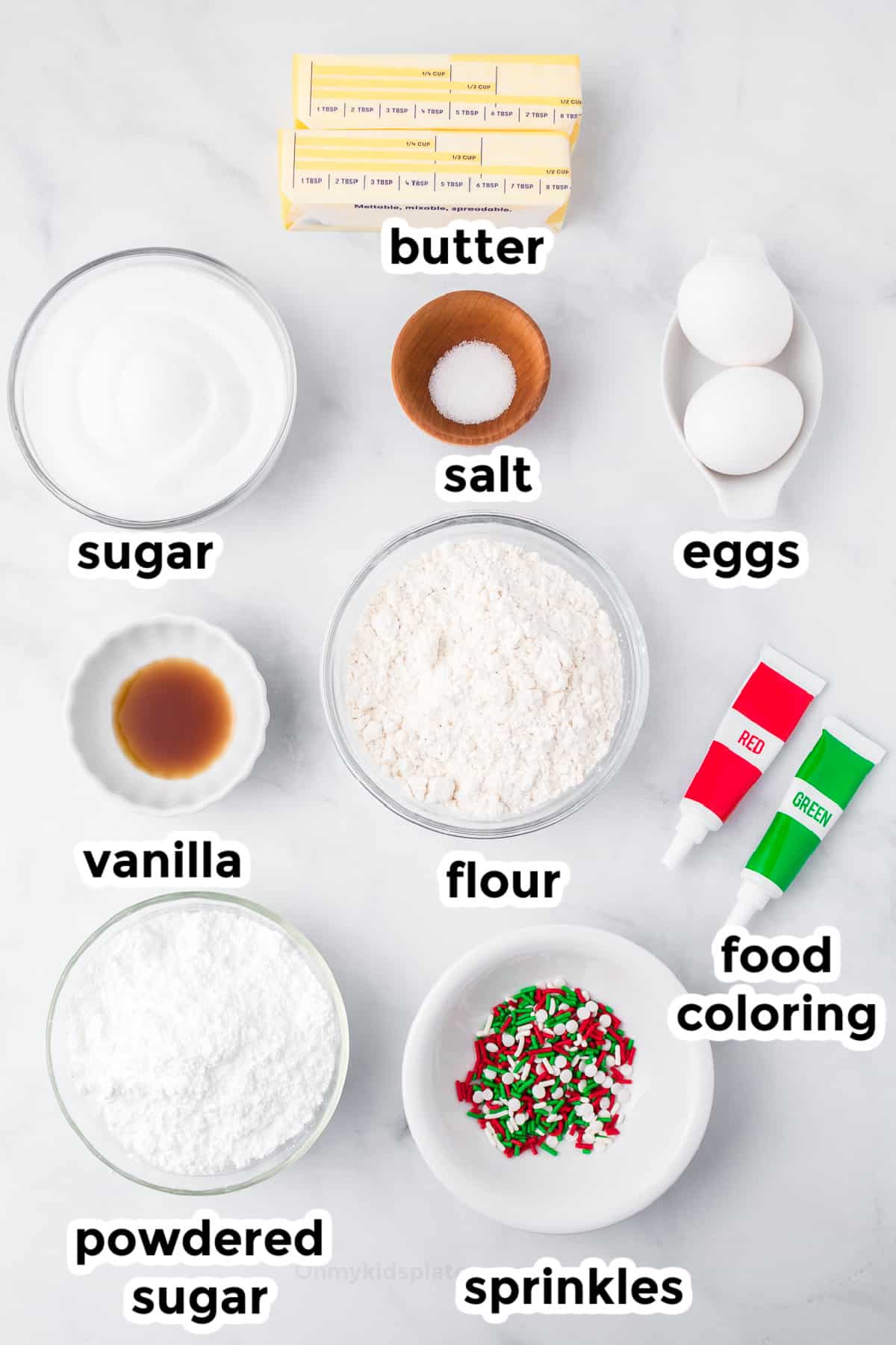 Ingredients for sugar cookies and frosting on a counter in bowls from overhead.