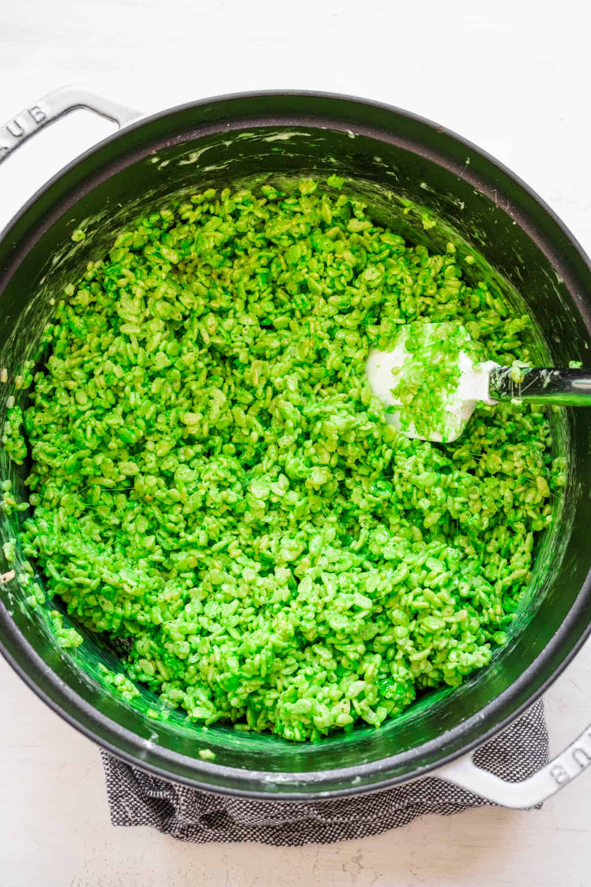 Green Rice Krispie treat mixture in a pot from overhead on a counter.