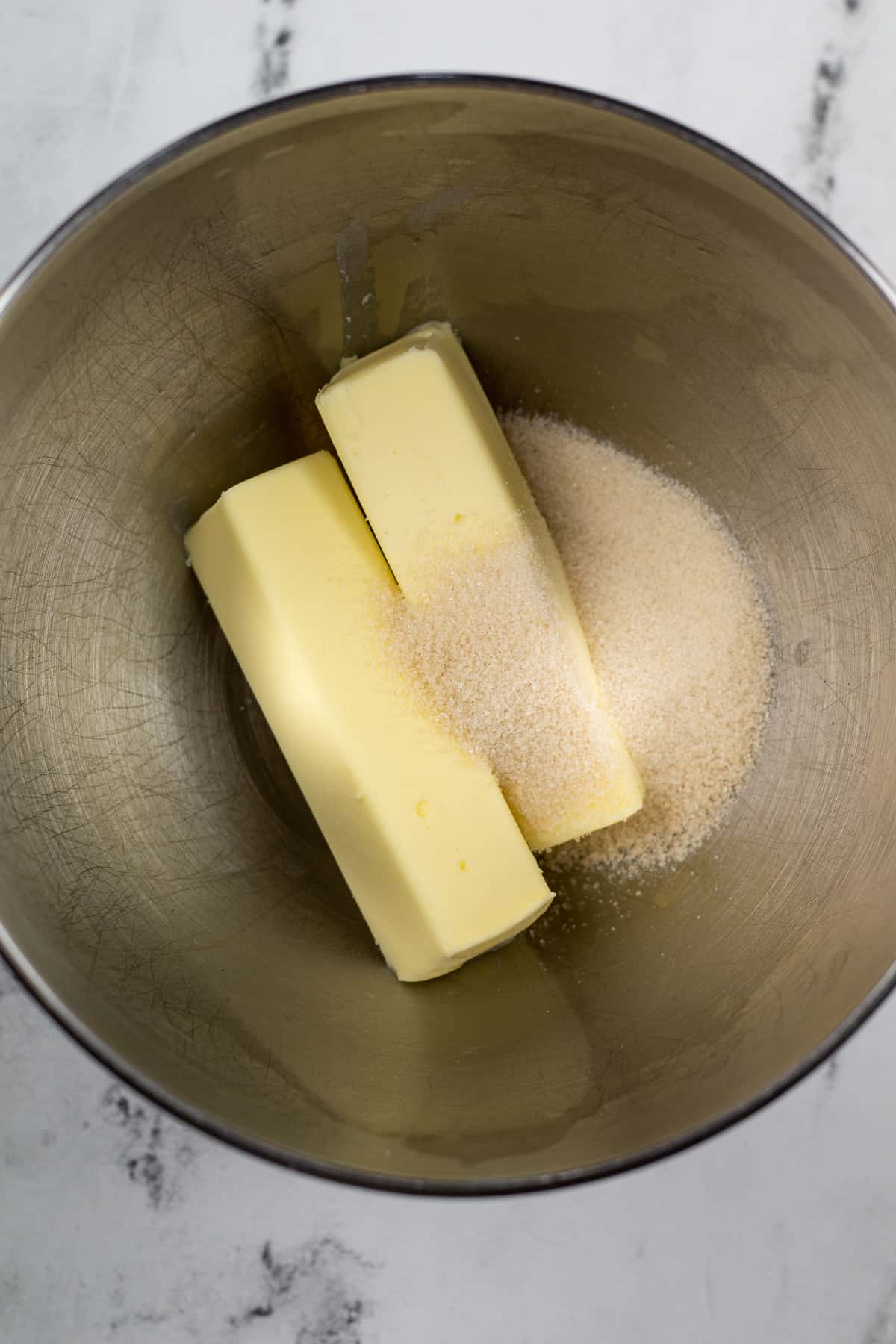 Butter and sugar in a large mixing bowl from overhead on a counter.
