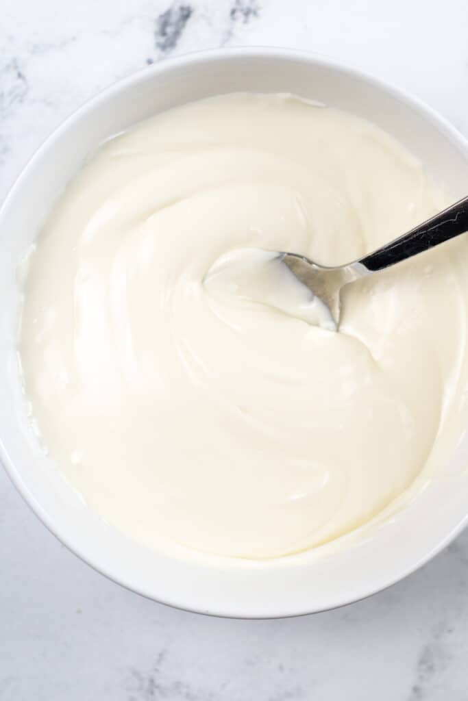 Melted white chocolate in a bowl from overhead on a counter for sugar cookie fudge.