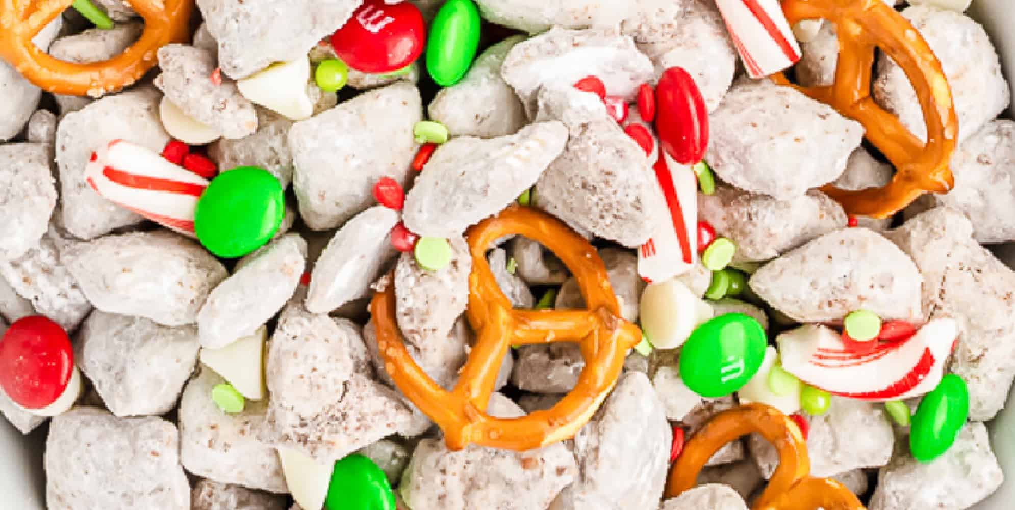 Close up on the reindeer chow chex mix party mix to see pretzels, puppy chow, candy cane bits, M&Ms and sprinkles wide view.