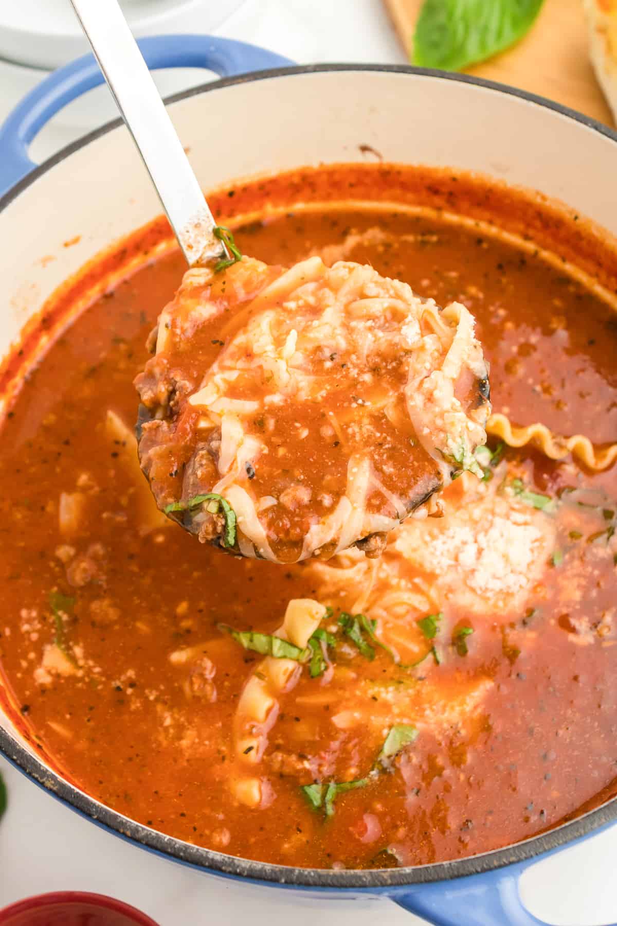 Lasagna soup being scopped from a large pot from overhead with a ladle.