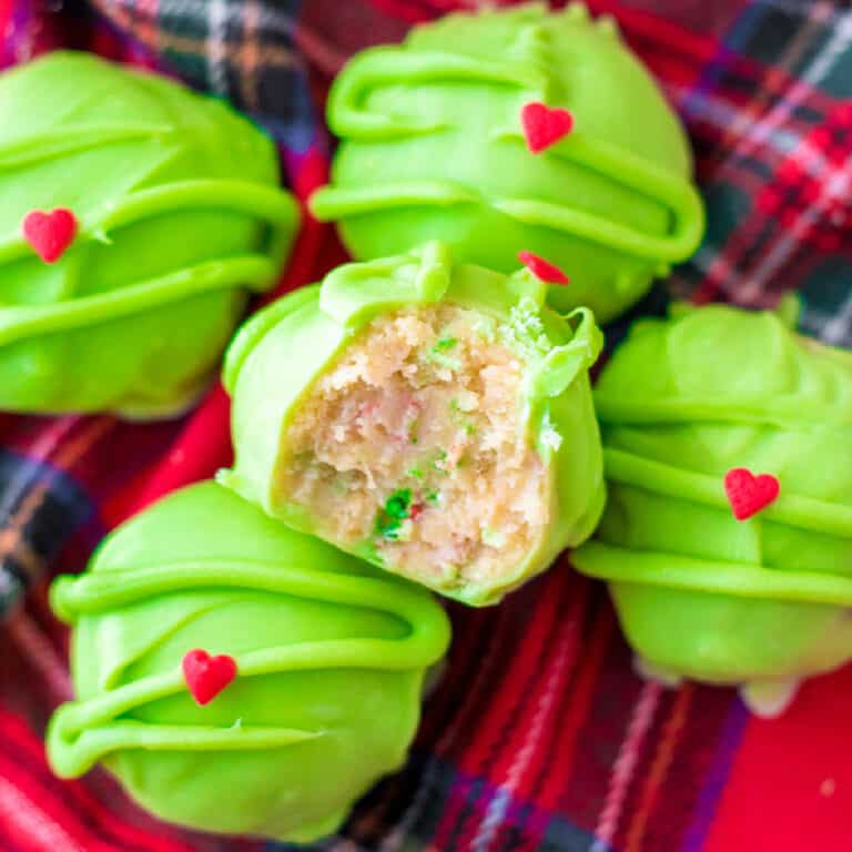 Close up square view of a green grinch golden oreo ball stacked from above with the top truffle missing a bite.