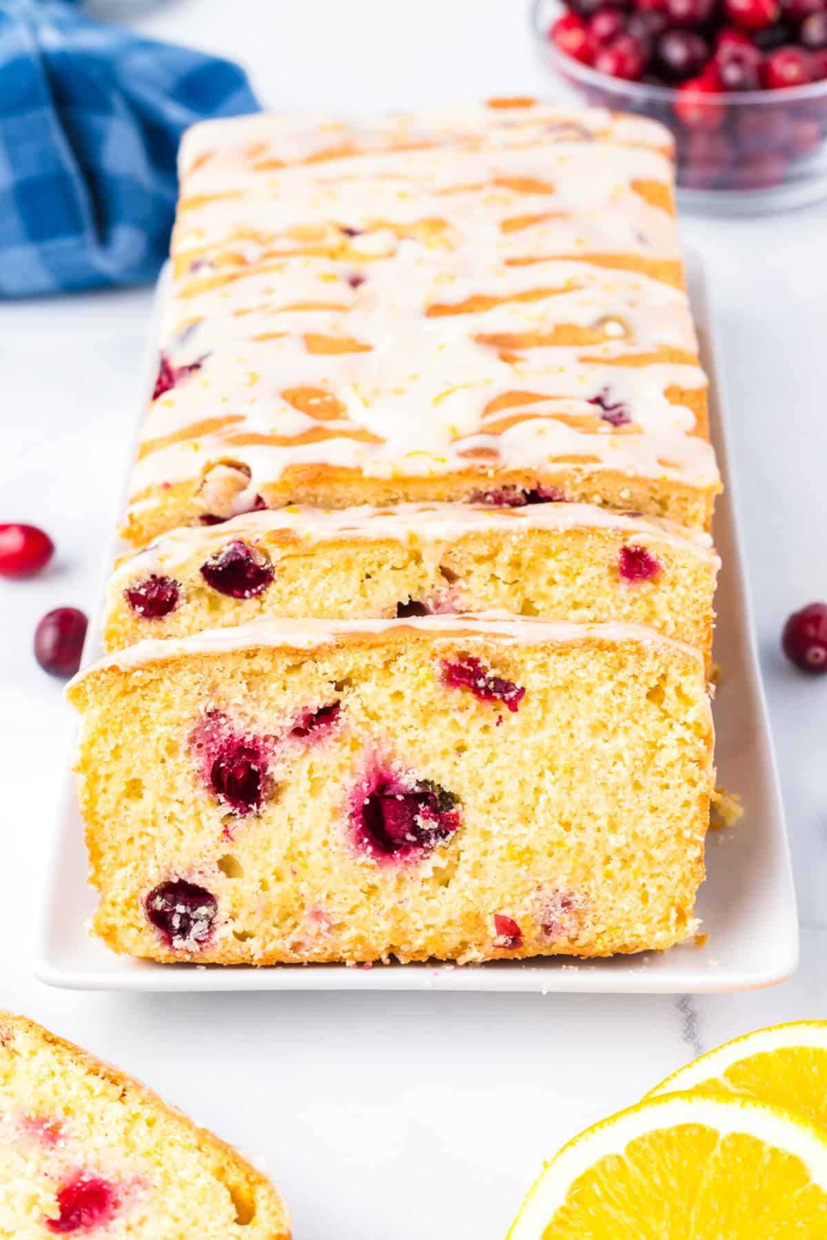 Cranberry orange bread with glaze sliced from the end to show the cranberries inside. on a platter from the end.