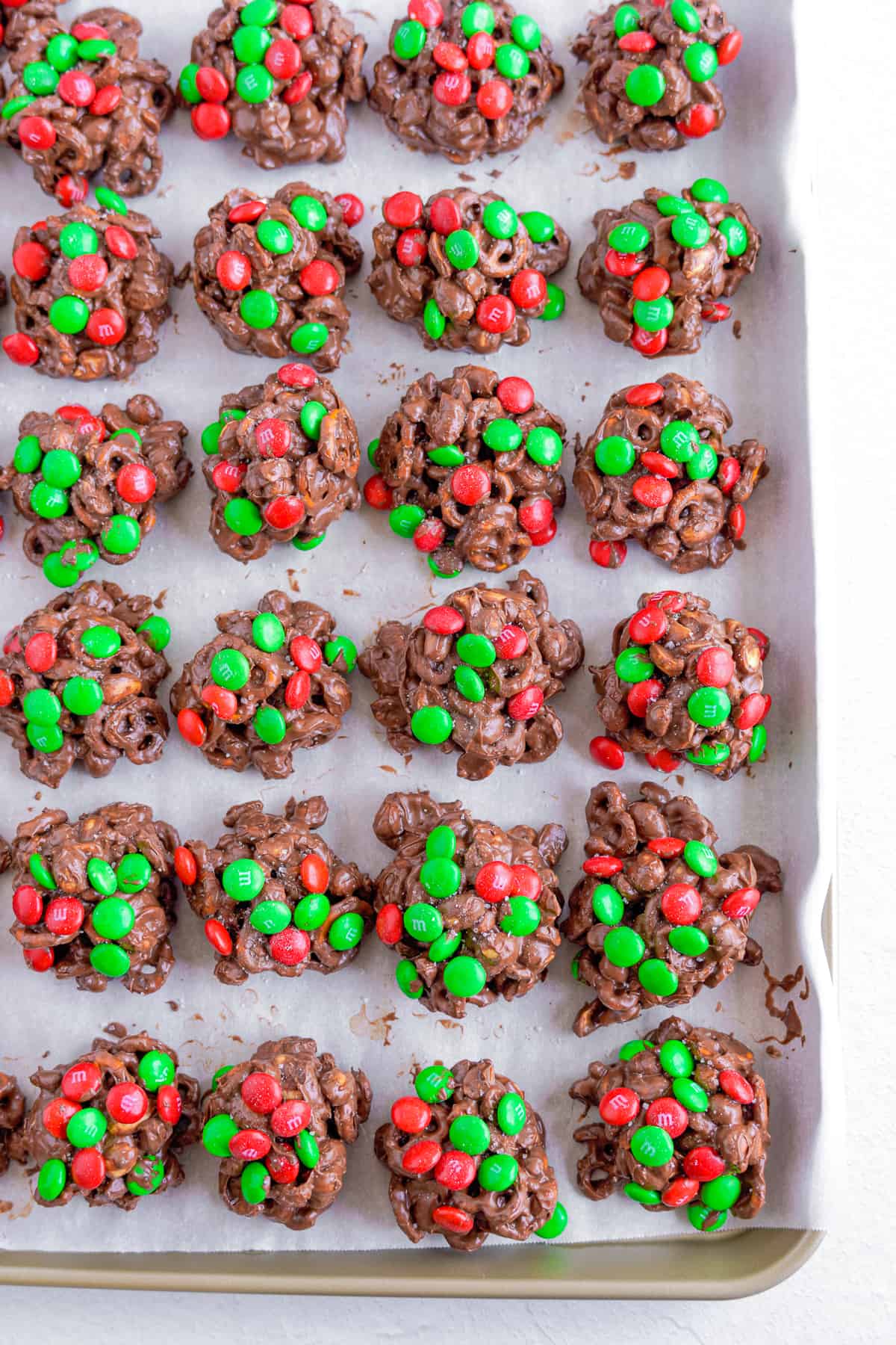 Chocolate crockpot candy lined up in rows on a parchment paper lined pan from above.