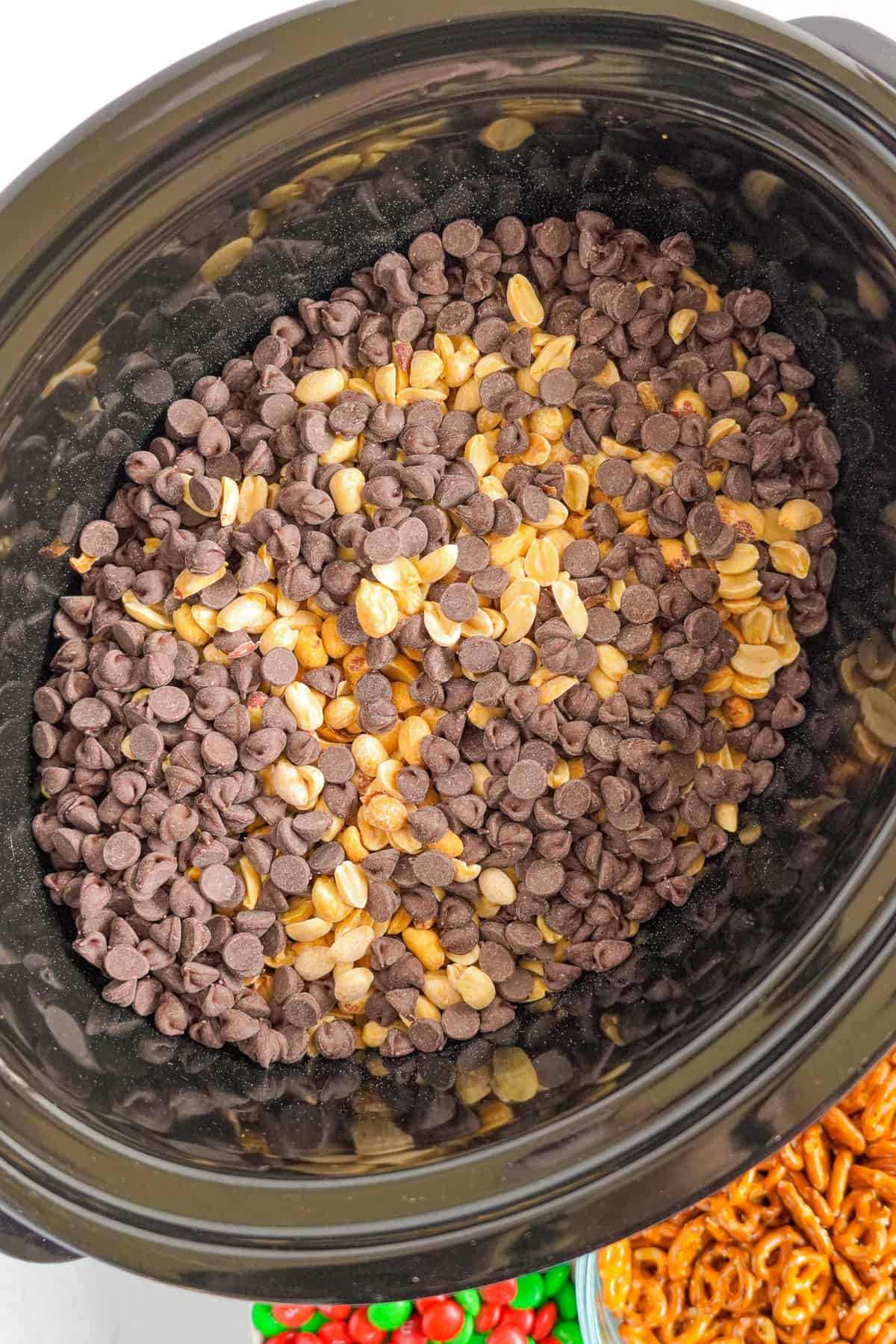 Chocolate chips and peanuts layered in a crockpot from above.