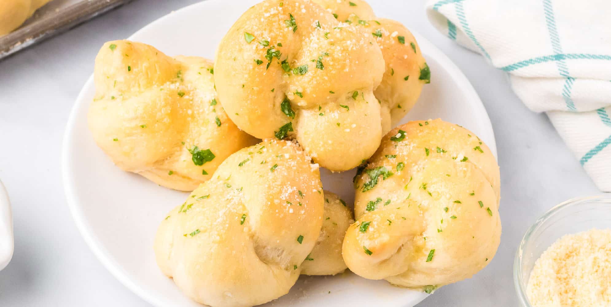 Close up wide view of garlic knots stacked on a plate.