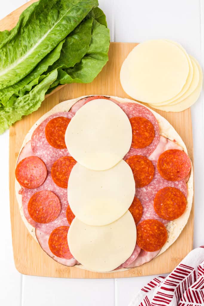 Adding provolone cheese to the center of the Italian pinwheel tortilla.