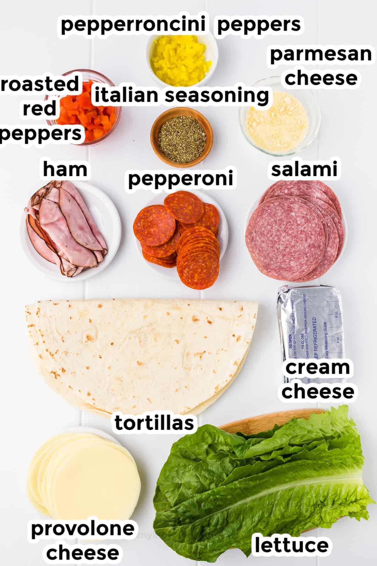 Ingredients for italian pinwheels in bowls on a counter from overhead with text labels.