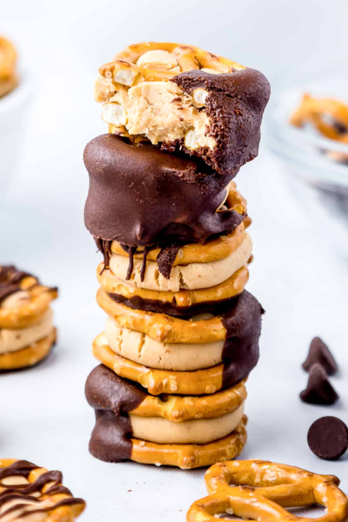 Peanut butter pretzel bite buckeyes stacked in a tall stack with the top piece missing a bite.