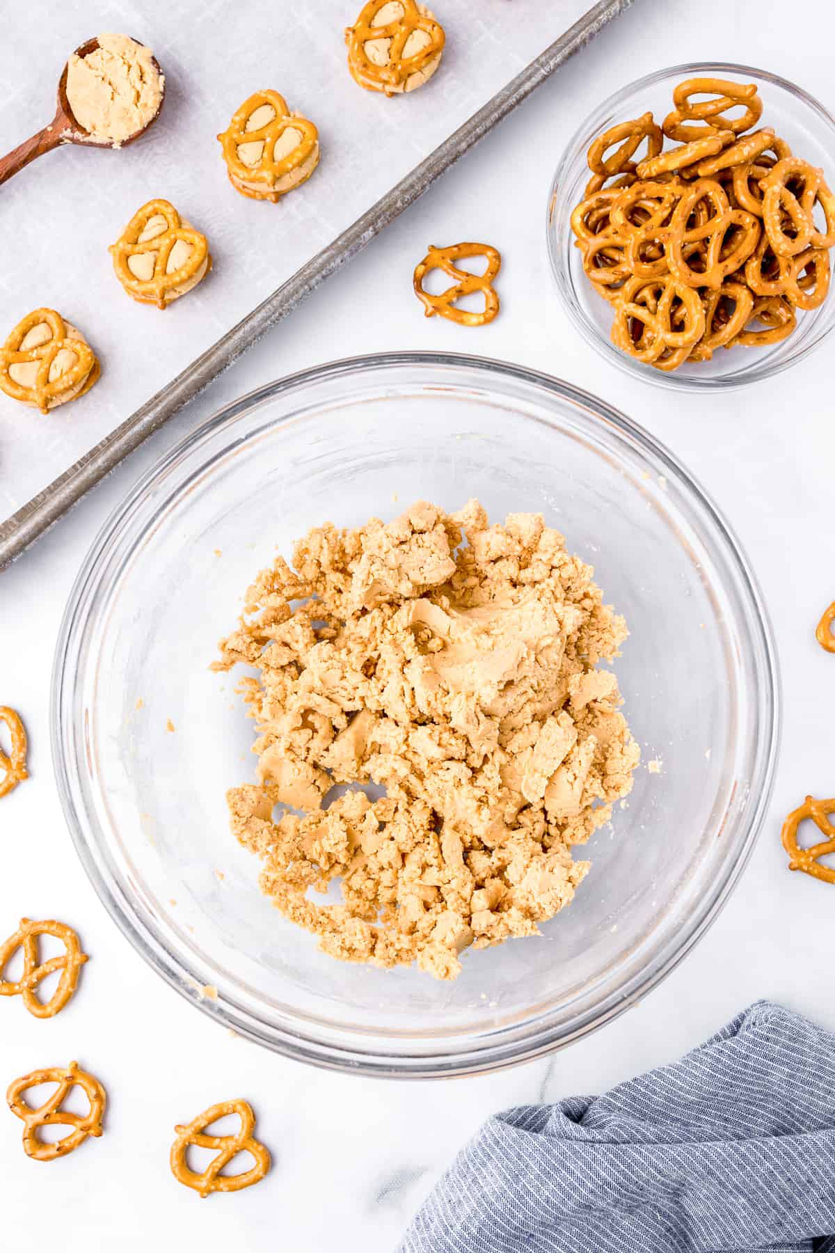 Peanut butter pretzel bites dough in a large bowl from overhead with pretzels and some prepared pretzel bites on a cookie sheet nearby.