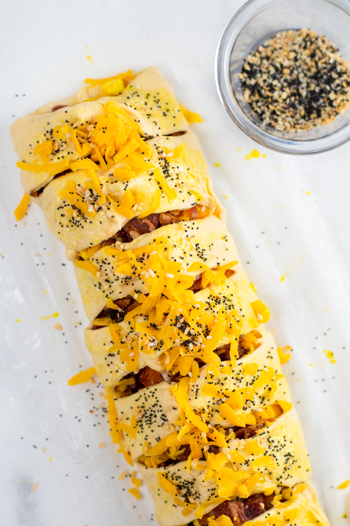 Breakfast crescent roll braid covered in cheese and everything bagel seasoning.