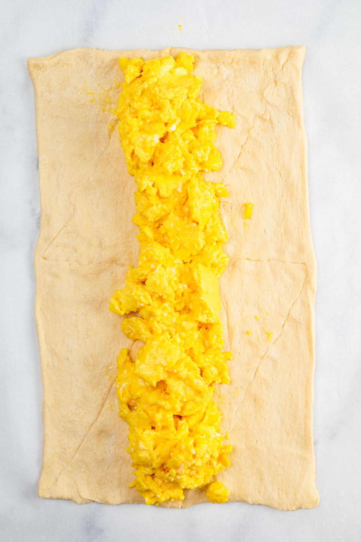 Scrambled eggs layered down the center of a sheet of crescent dough.