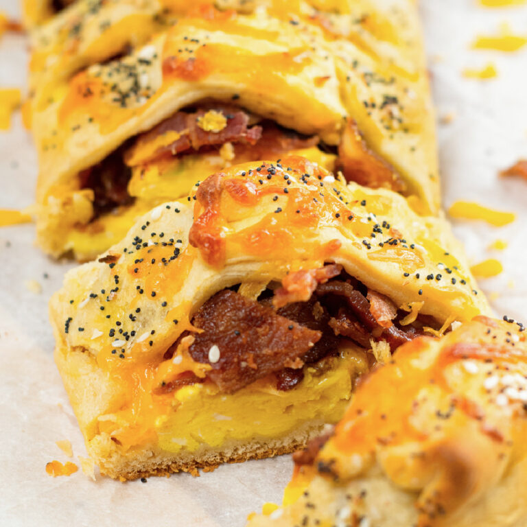 Close up sliced breakfast bread with bacon, egg and cheese wrapped in crescent roll dough showing the inside of the slice.