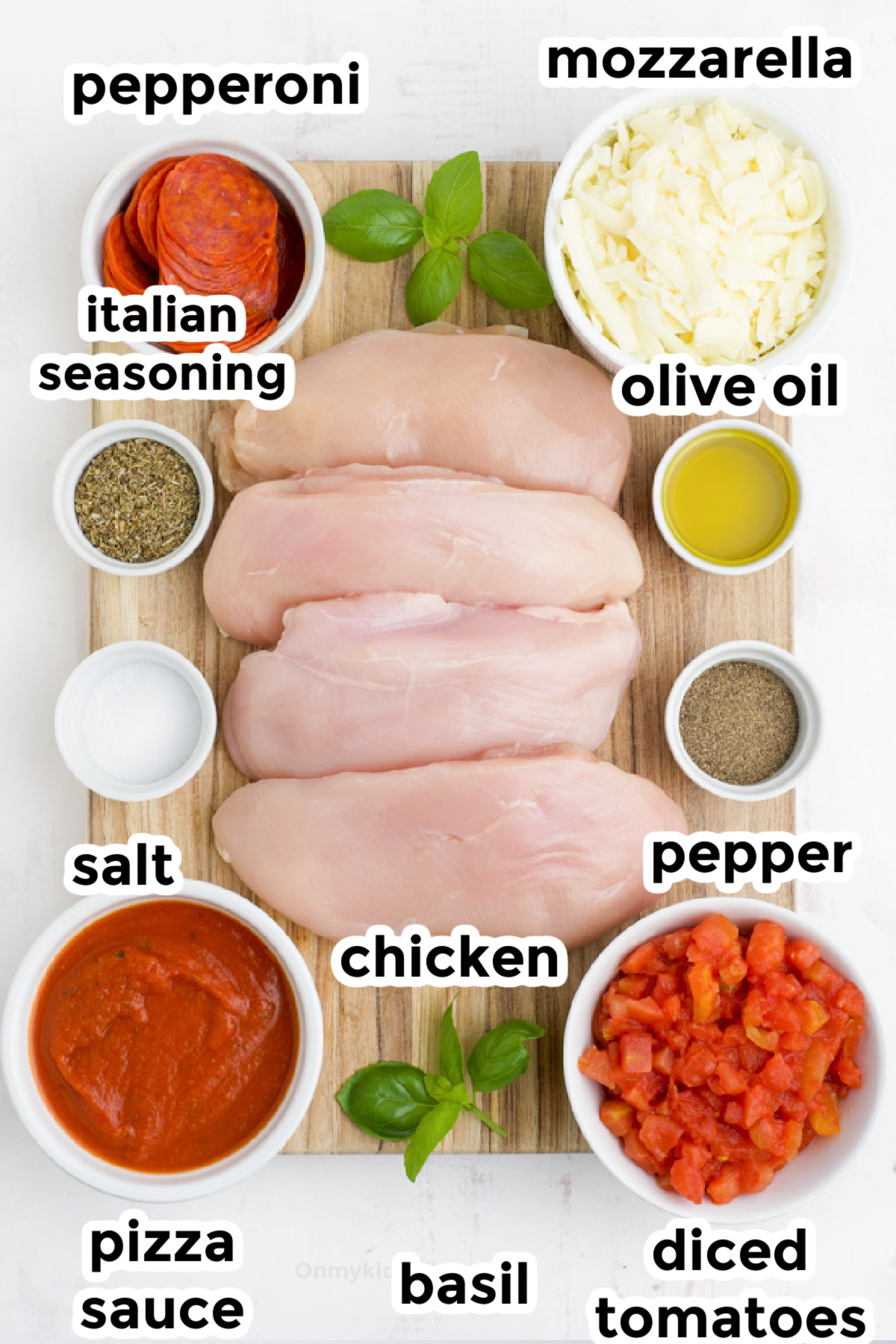 Ingredients for stuffed pizza chicken on a cutting board and in bowls from overhead with text labels.