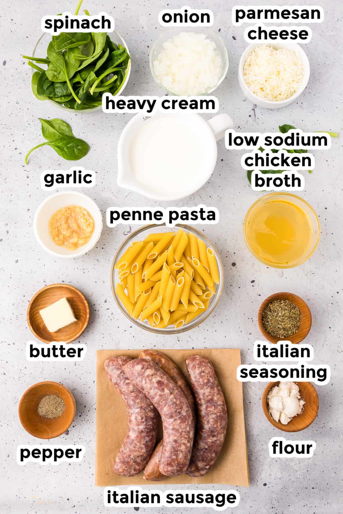 Ingredients for creamy sausage pasta in bowls and on a cutting board from overhead with text labels.