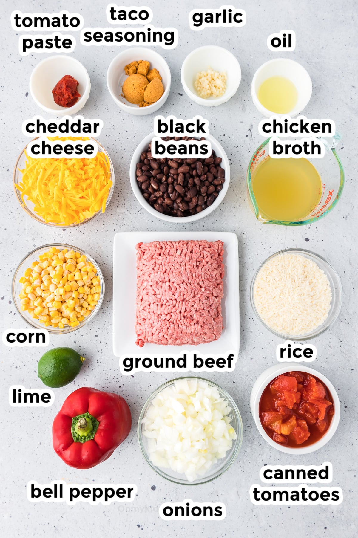 Ingredients for ground beef burrito bowls on a counter in bowls from above with text labels.