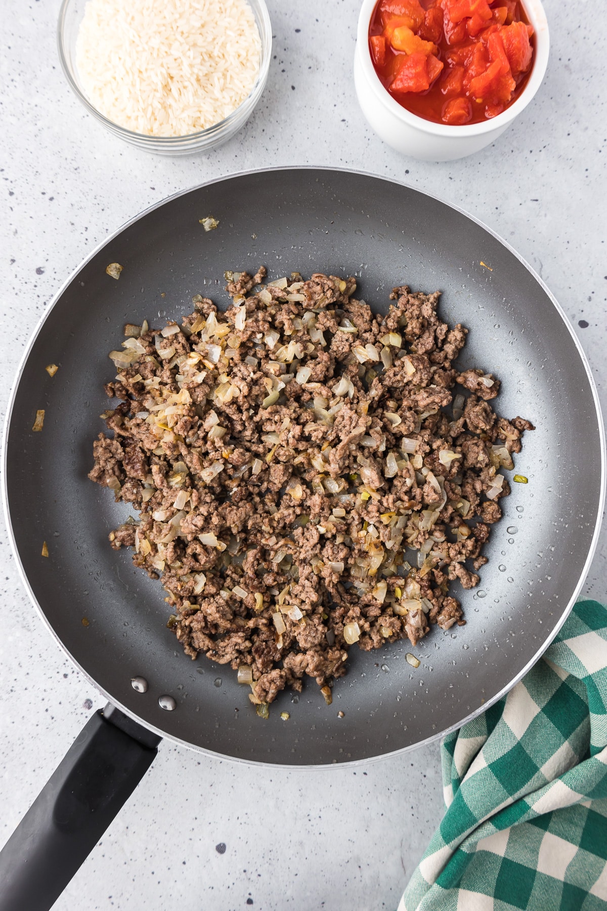 Ground beef cooked until brown in a pan from overhead with grease drained.