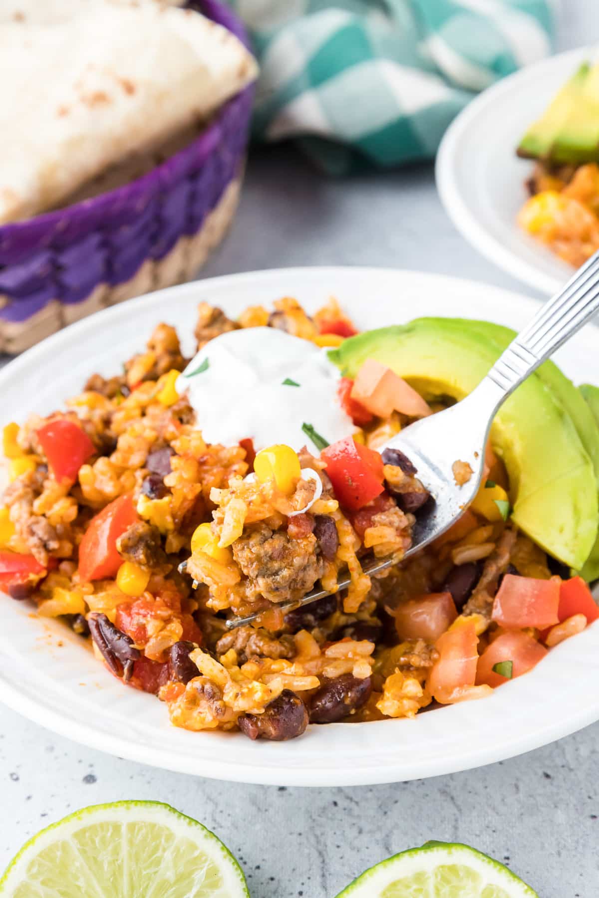 Ground beef burrito bowl full of toppings being scooped with a fork from the side.