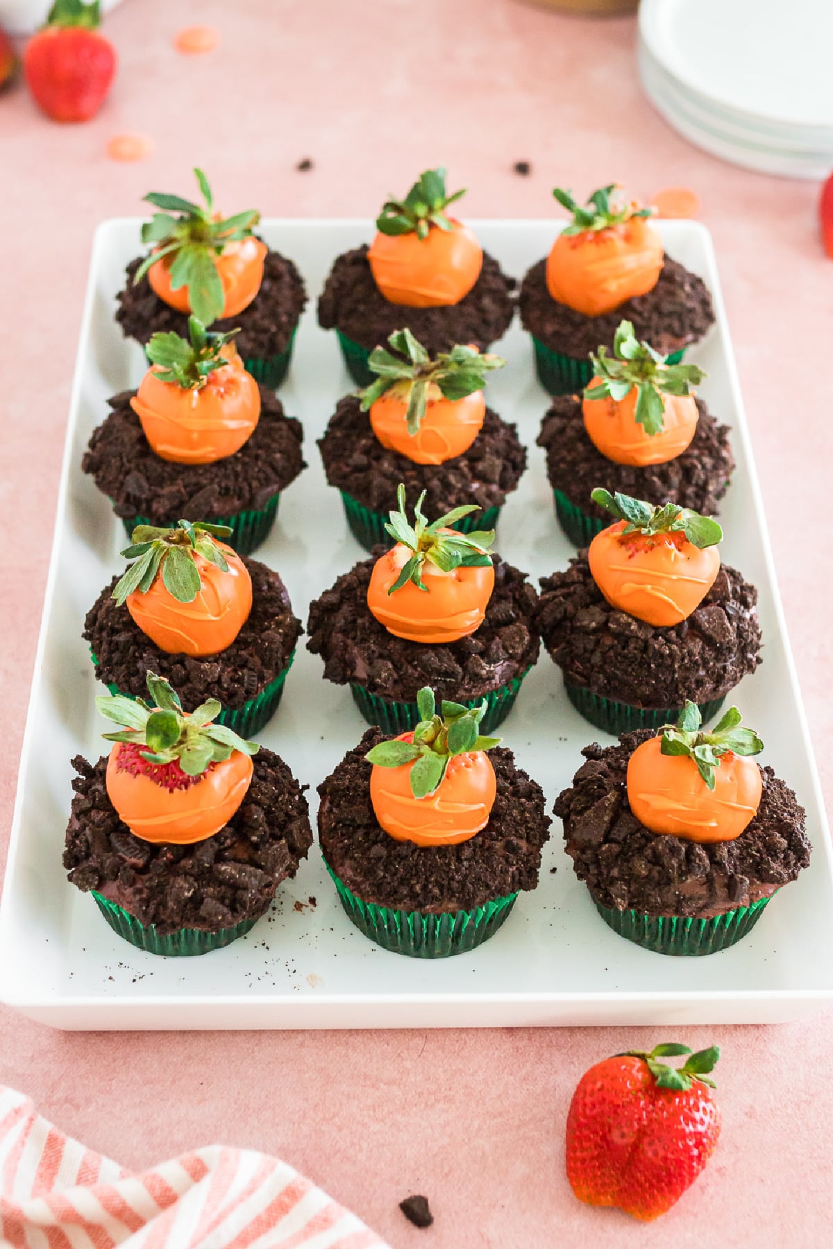 Platter full of decorated chocolate carrot patch cupcakes lined up in rows from the side.