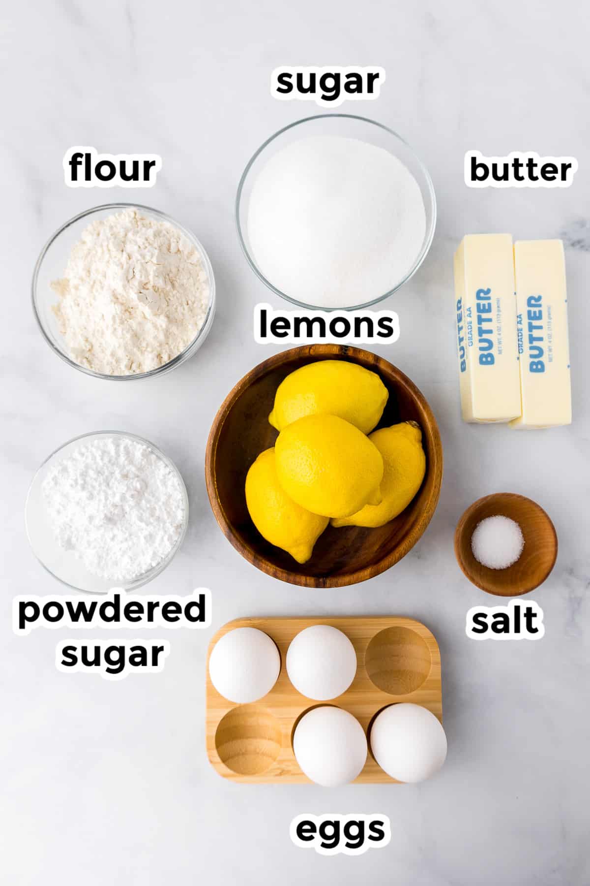 Ingredients for lemon bars in bowls on a counter from above with text labels,
