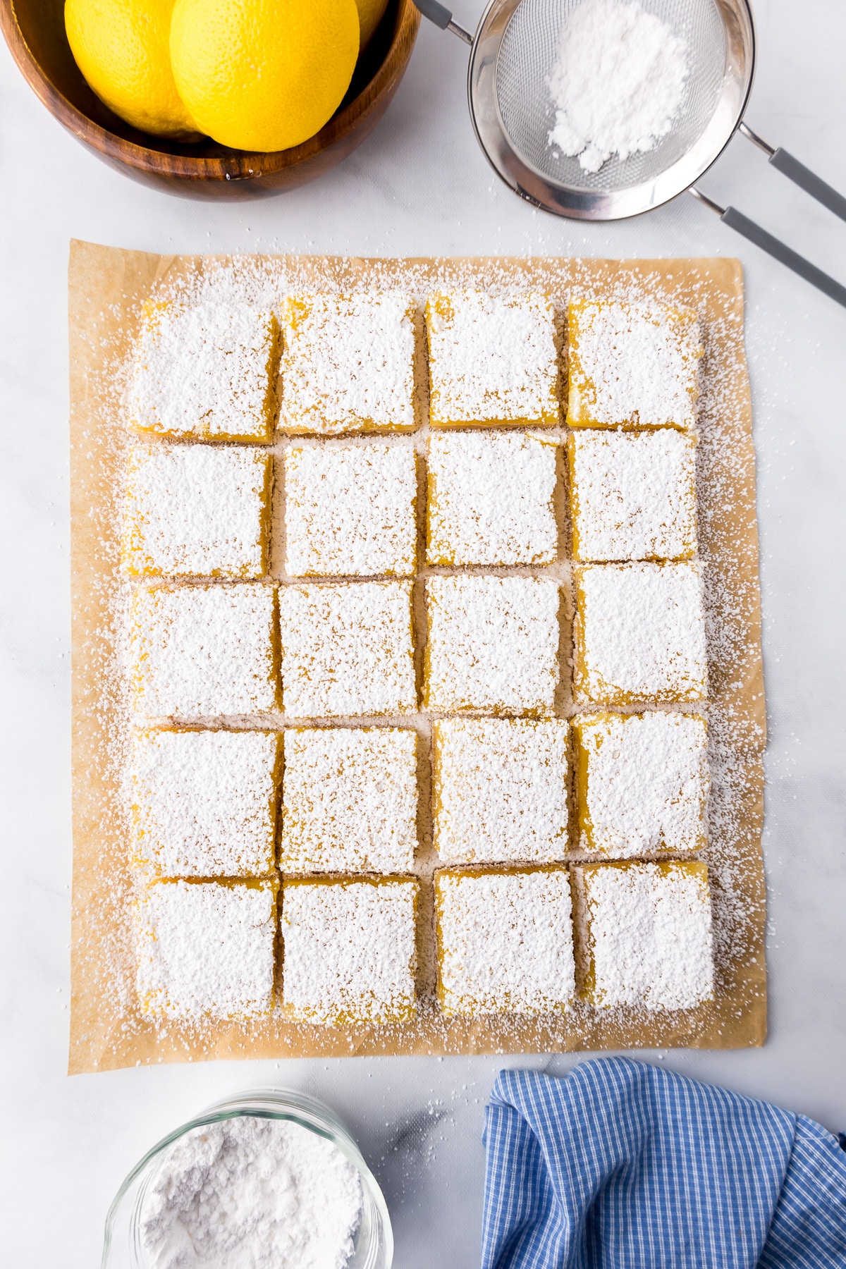 Lemon bars from overhead edges trimmed and sliced into squares, covered in powdered sugar.