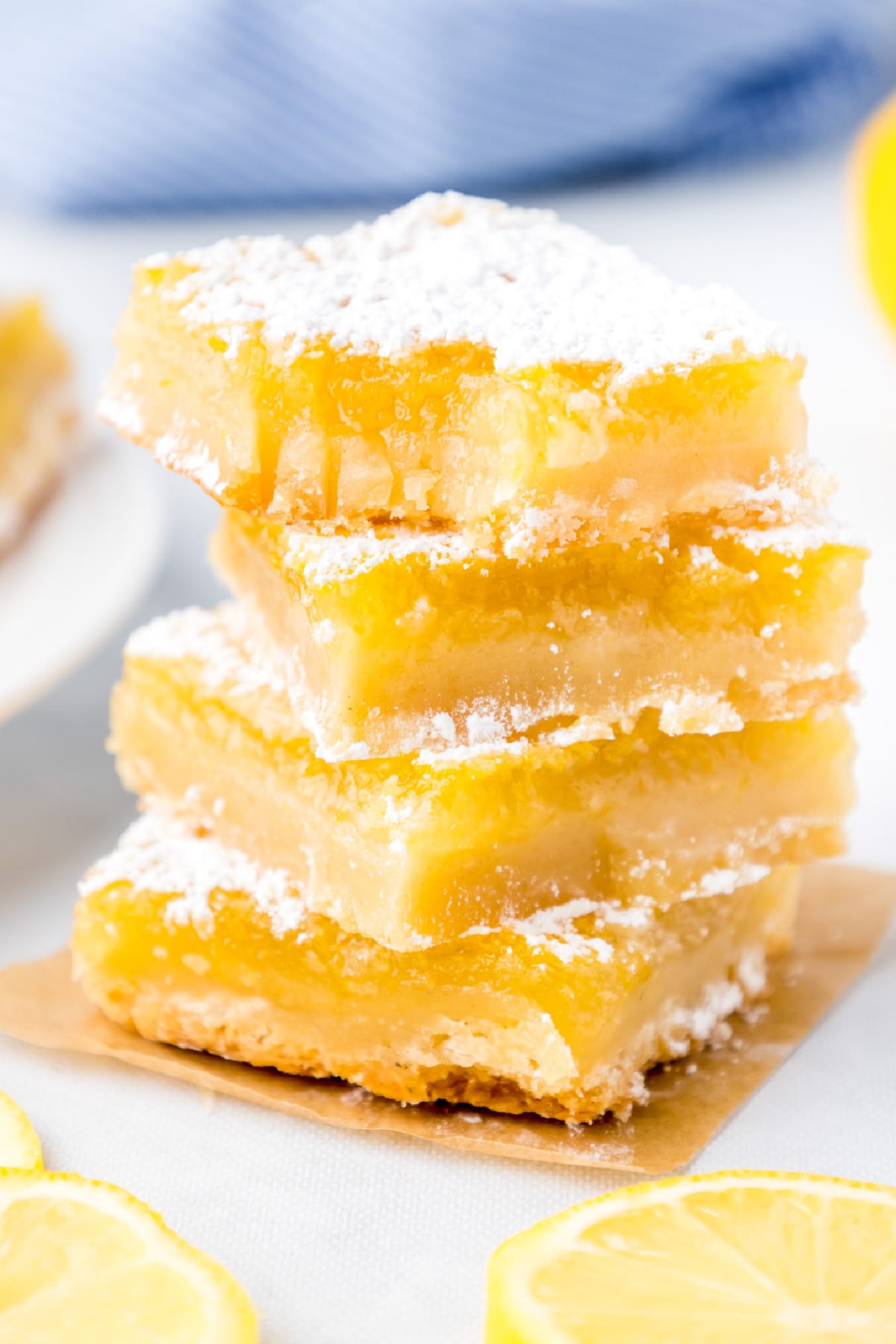 Lemon bars stacked four tall from the side with the top piece missing a bite.