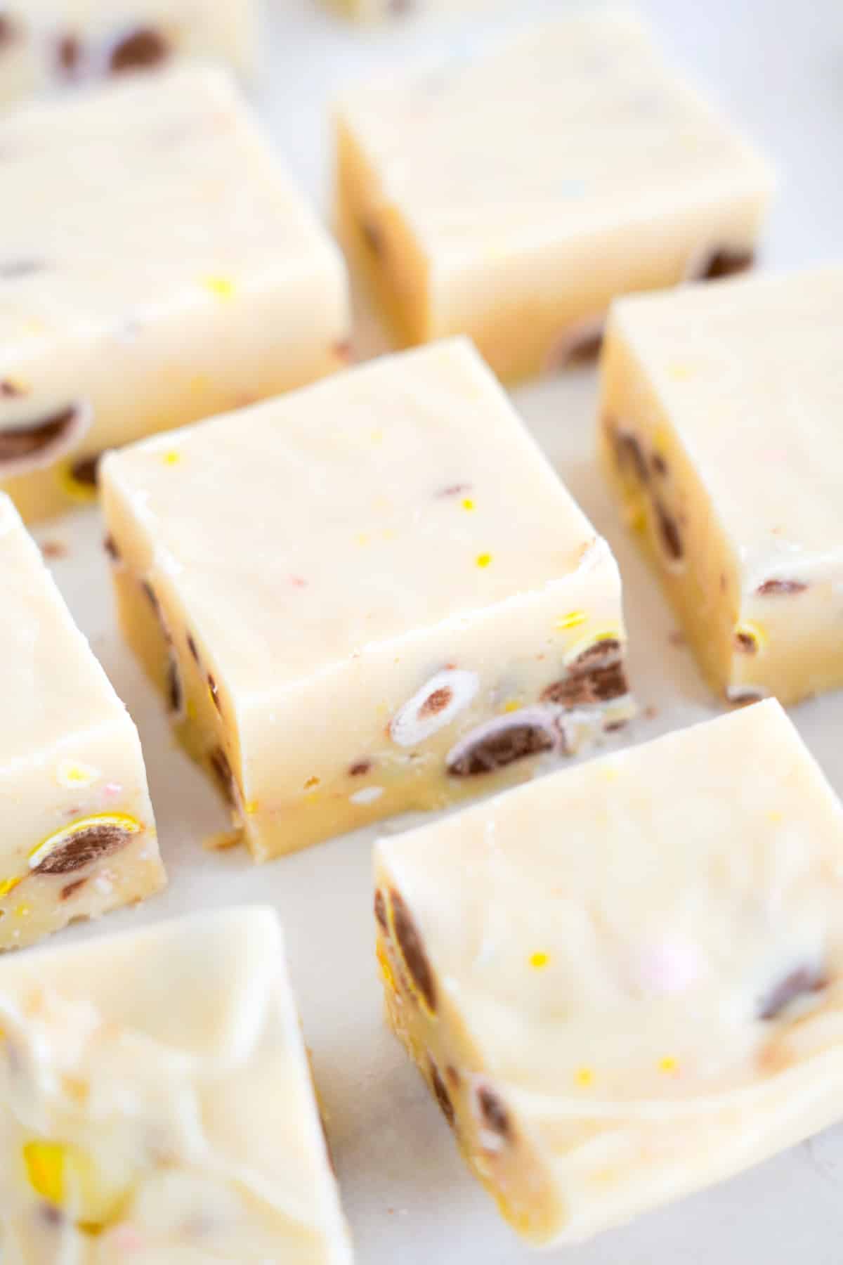 Slices of white chocolate fudge with chocolate mini egg bits inside close up on a counter.