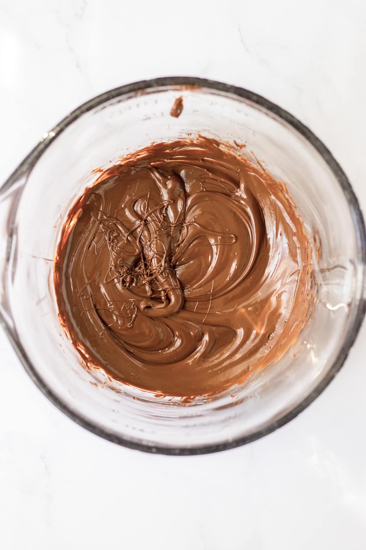 Melted chocolate in a glass measuring cup from above.