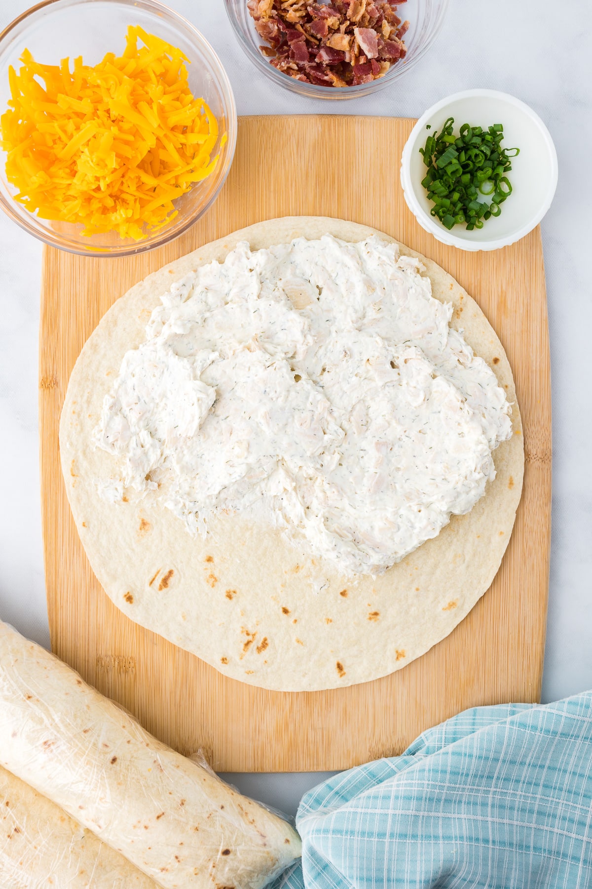 Spreading the cream cheese mixture on a large tortilla from overhead.
