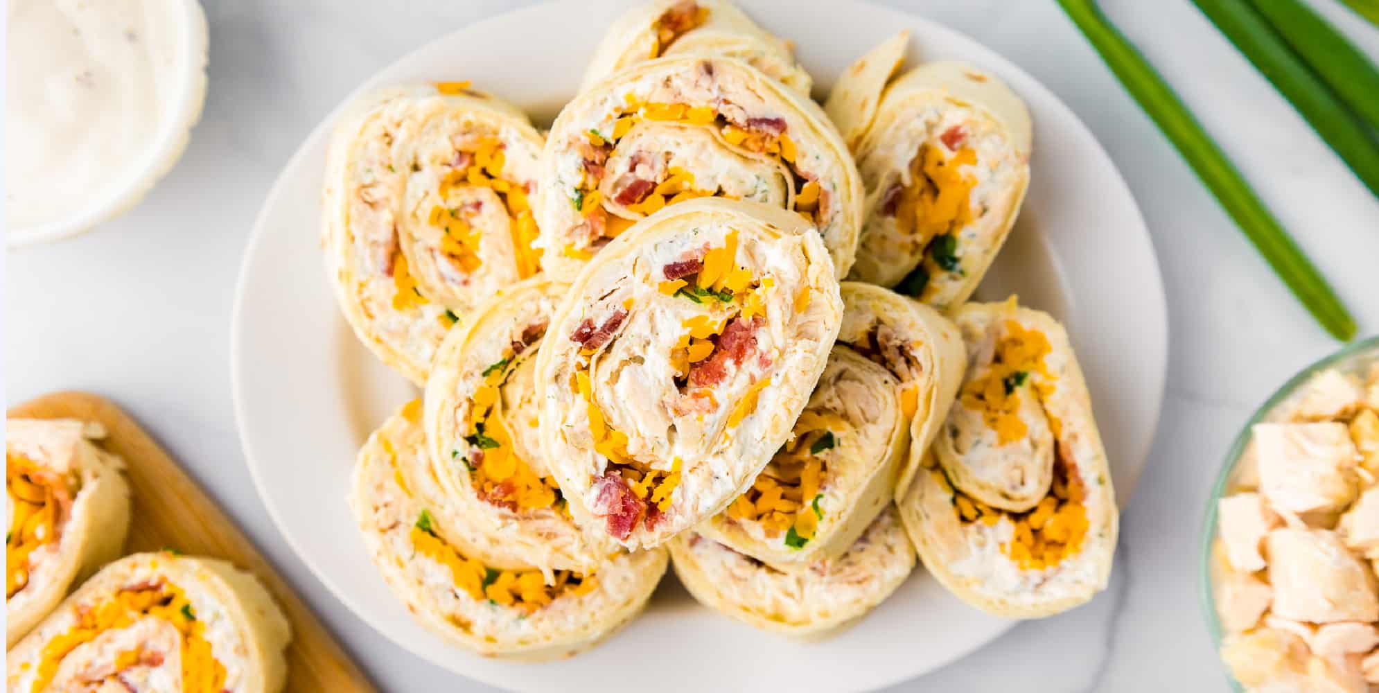 Wide view of chicken bacon ranch pinwheels stacked on a plate from overhead.