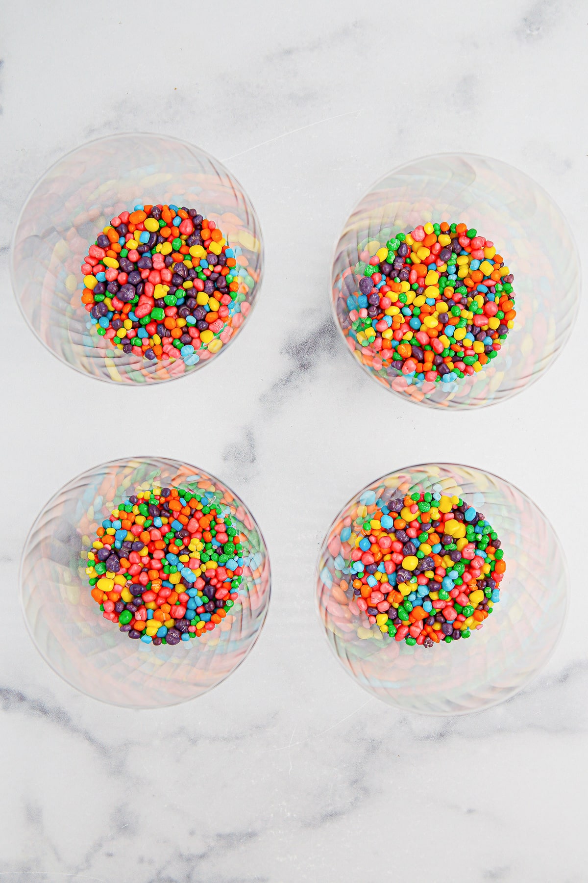 Nerd candies in four clear cups from overhead.