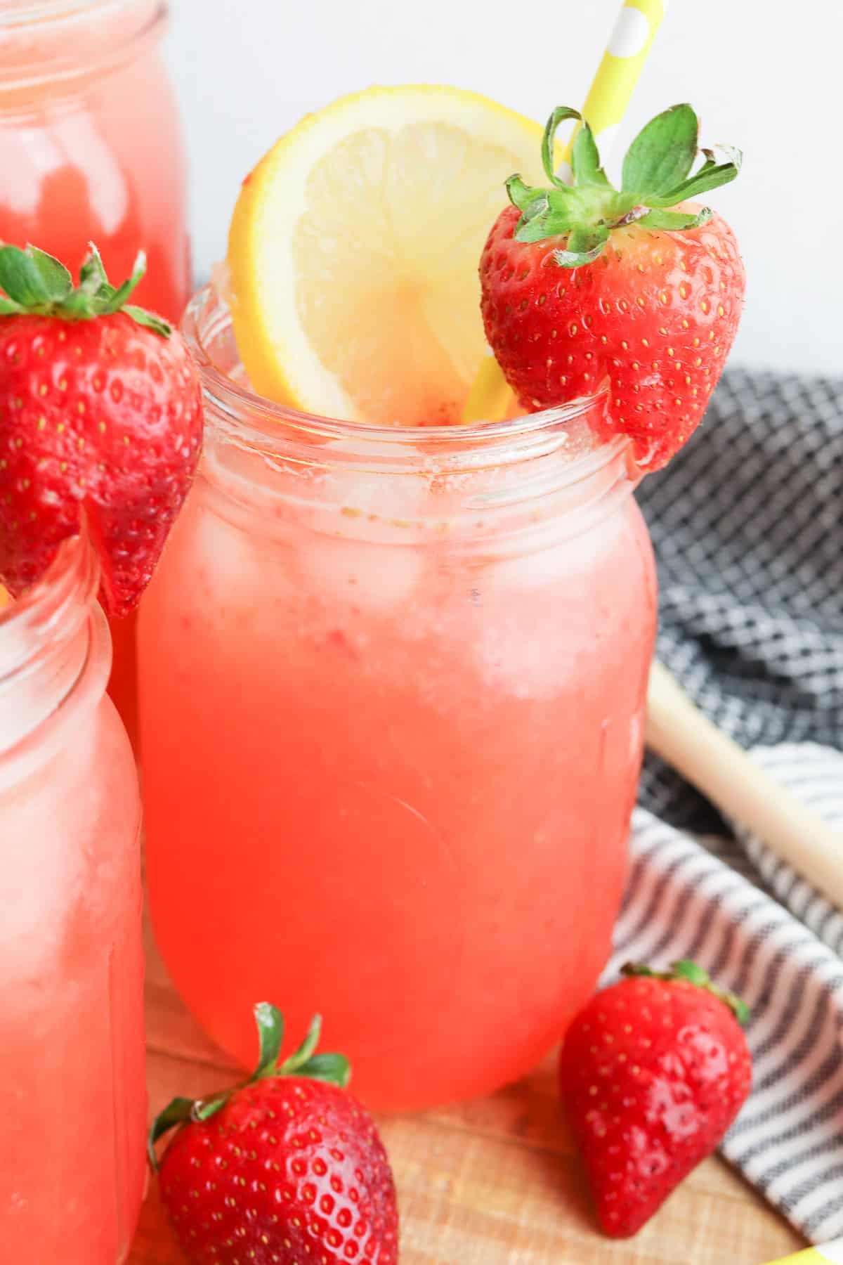 Up close view of a single glass of strawberry lemonade with more fresh strawberries on and next to the glass.