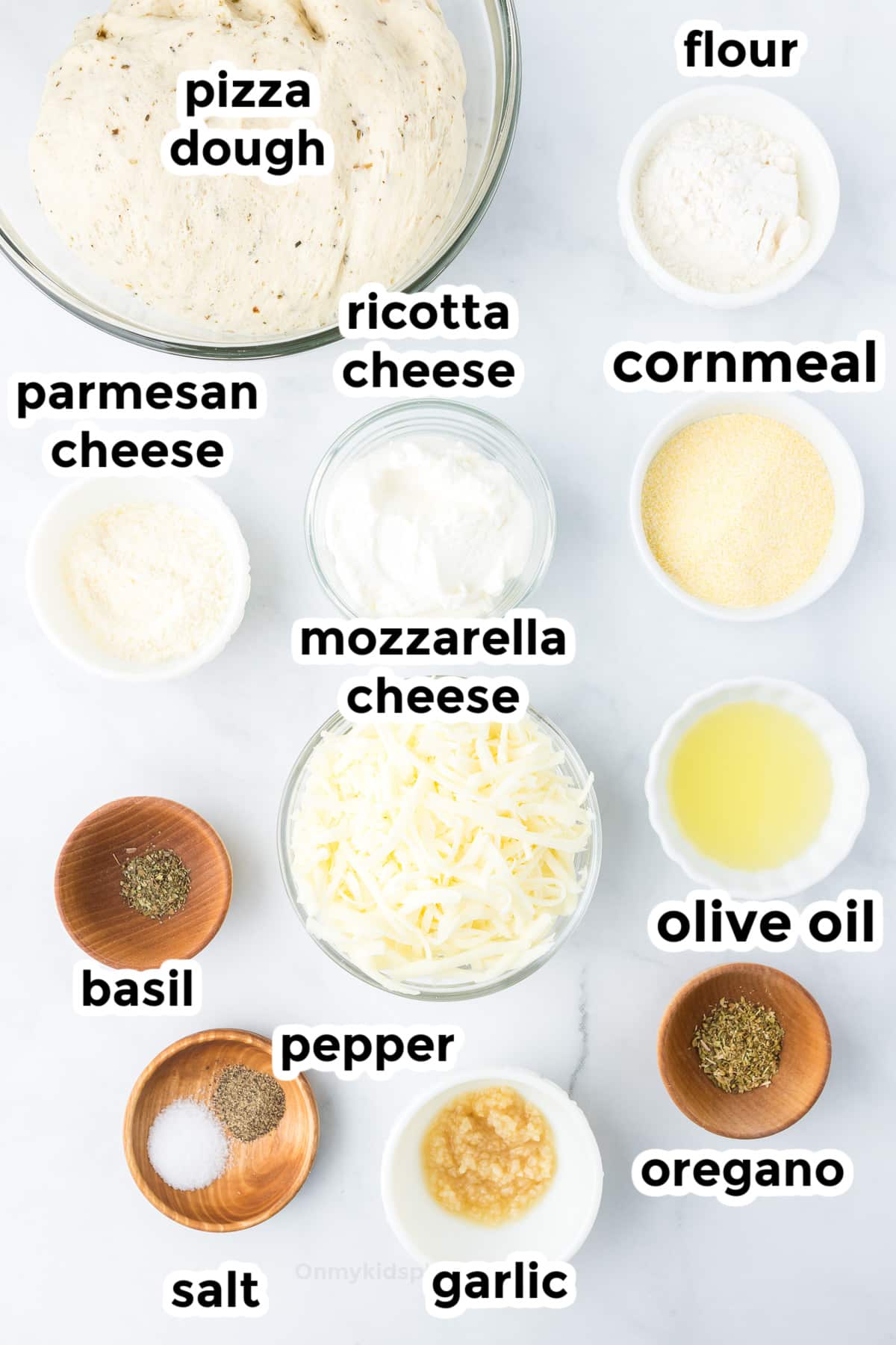 Ingredients for white pizza in bowls on a counter with text labels.