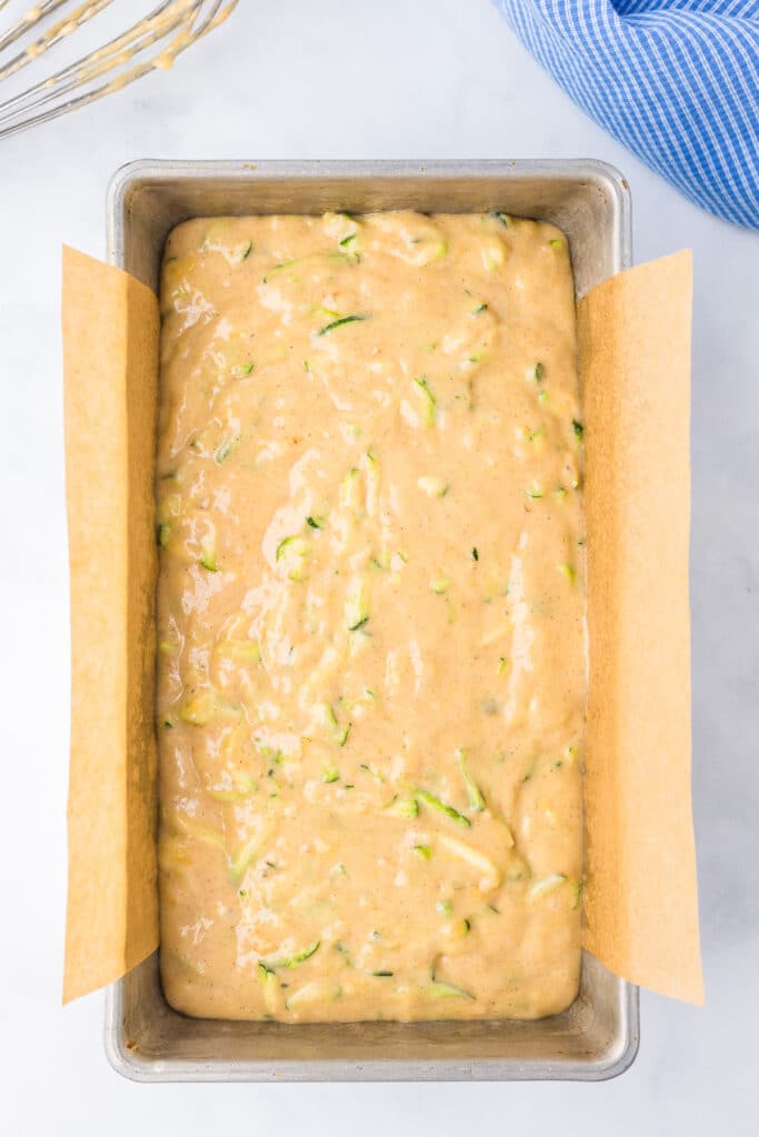 Finished zucchini banana bread batter in a bread pan lined with parchment paper from overhead.