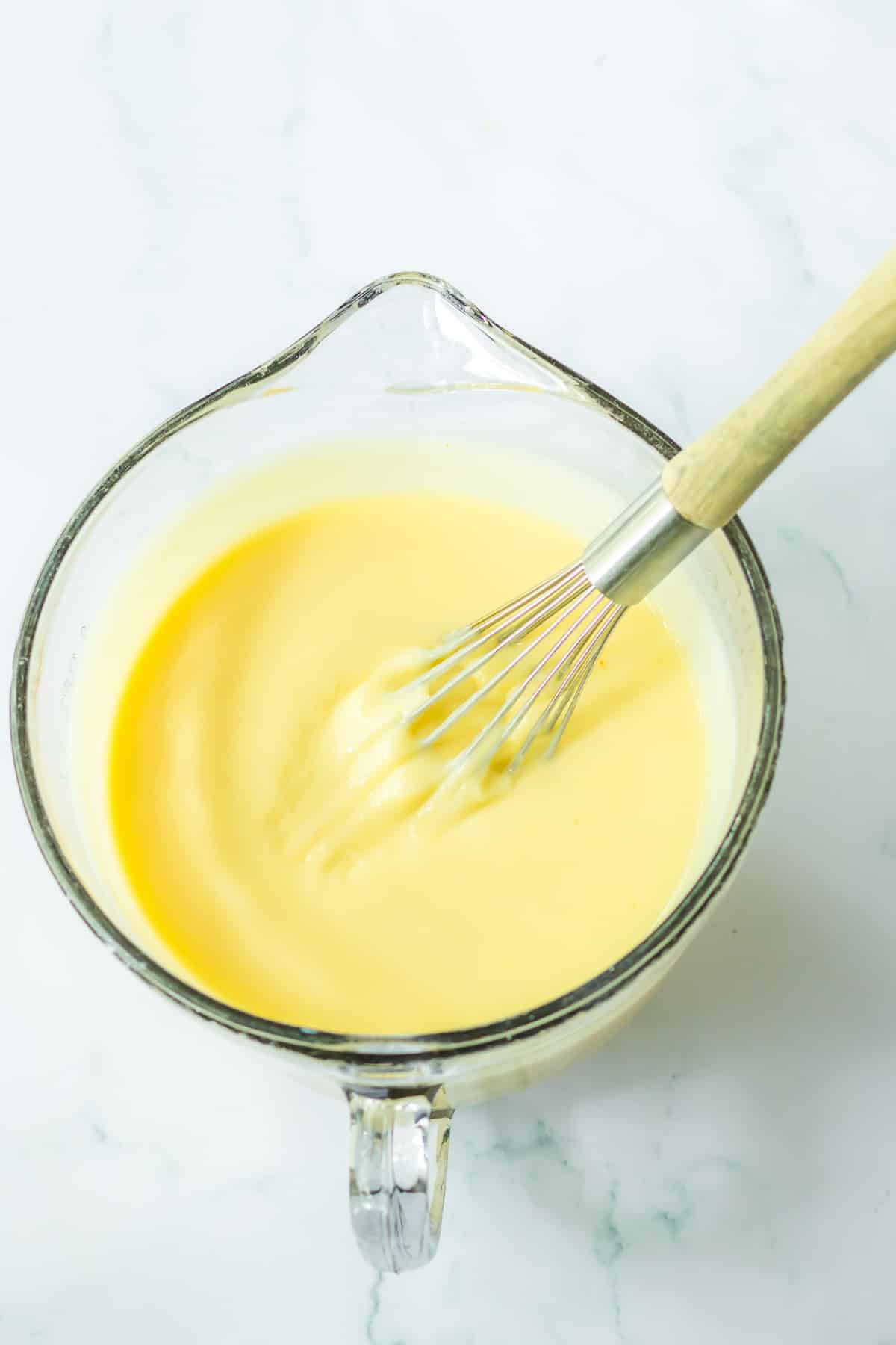 White pudding being mixed together with a whisk in a large mixing bowl from overhead.