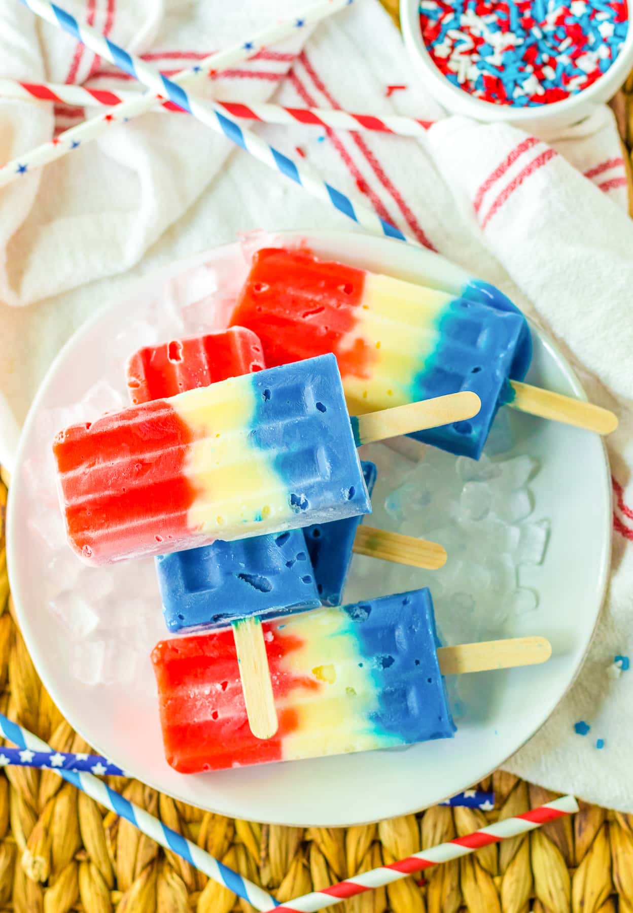 Red white and blue popsicles piled on a plate from above on a counter.