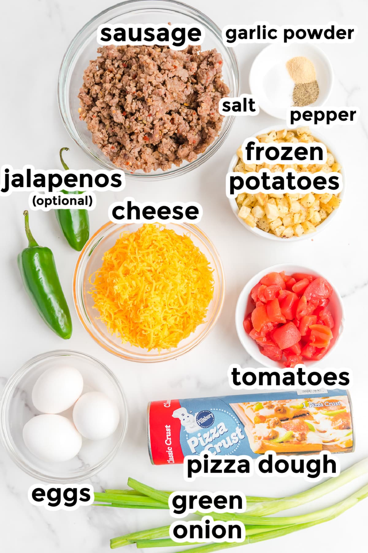 Ingredients for sausage breakfast pizza on a counter from above in bowls with title text labels.