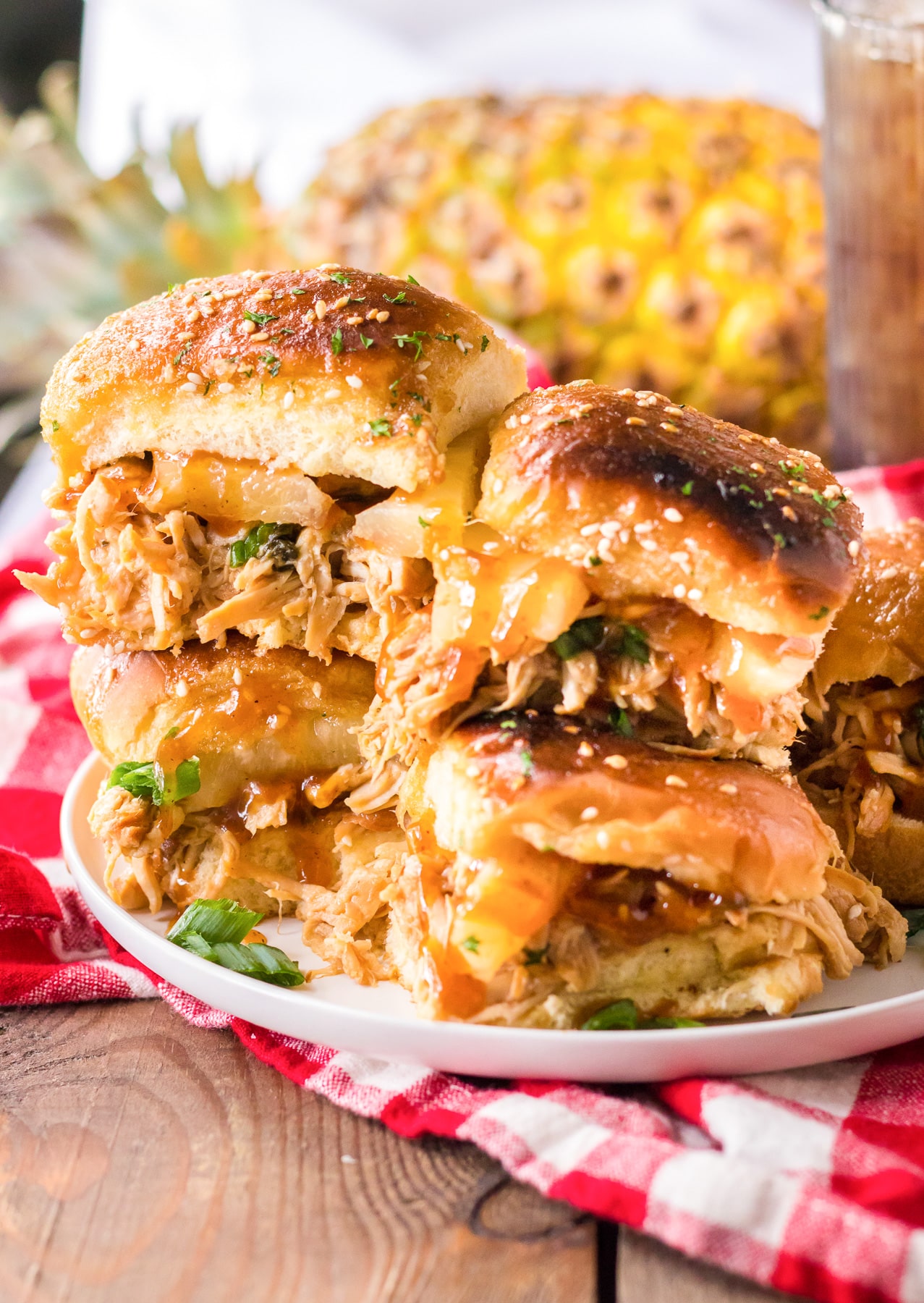 Full platter of bbq hawaiian roll chicken sliders piled high from the side on a table.