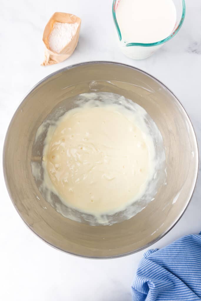Blended cream cheese and sweetend condensed milk with an open package of pudding and a measuring cup full of milk nearby.