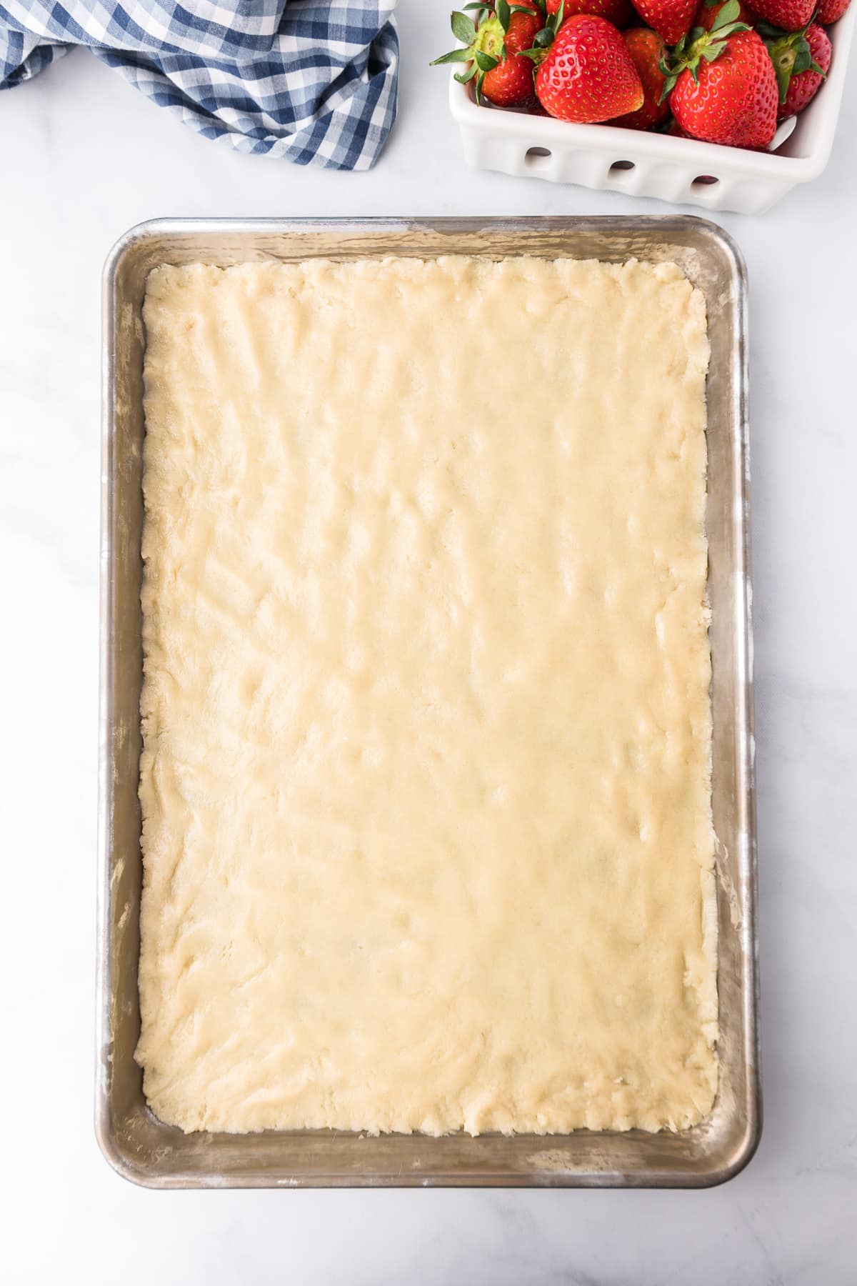 Sugar cookie dough pressed into a sheet pan from overhead.