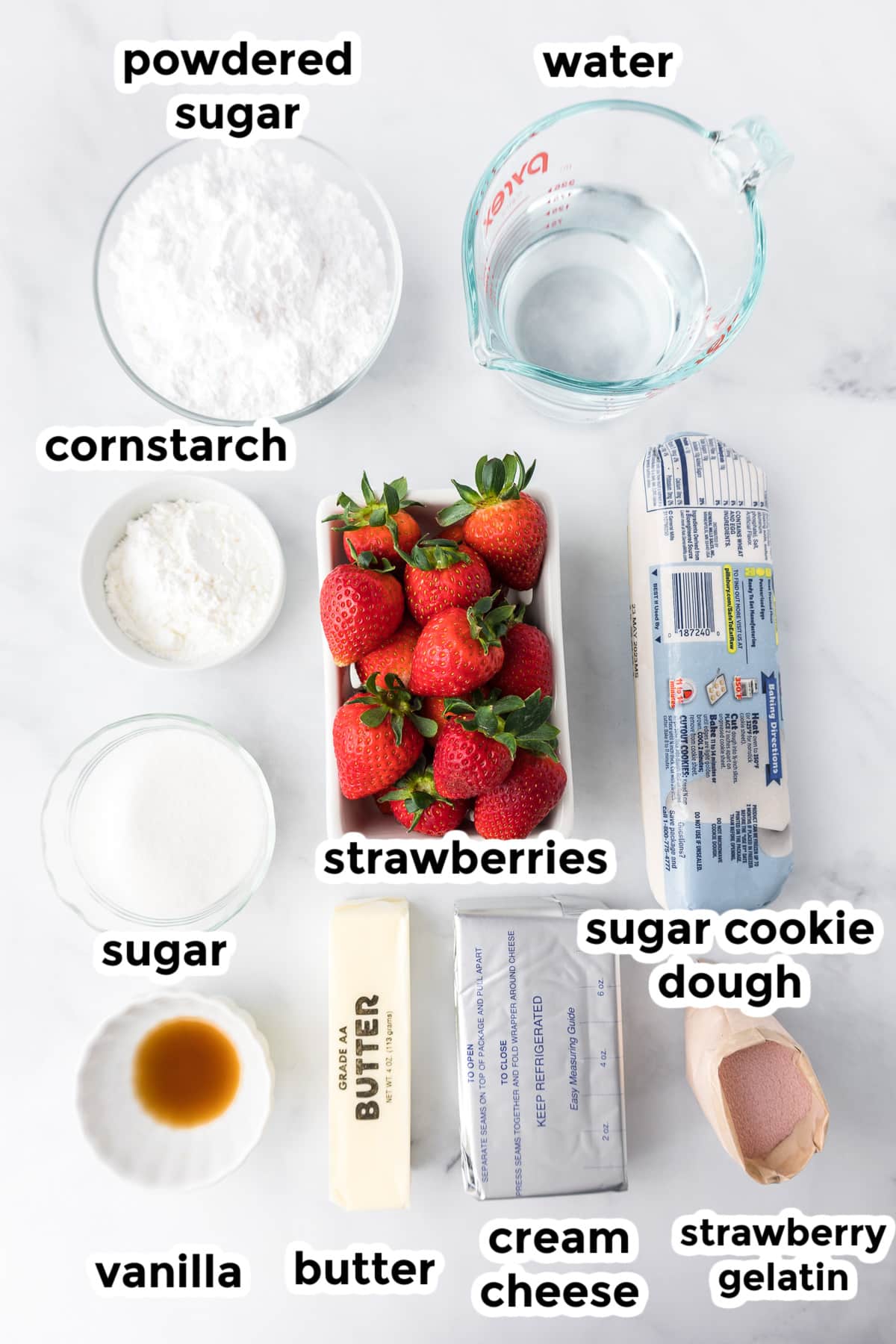 Ingredients for strawberry pizza in bowls on a counter from overhead with text labels.